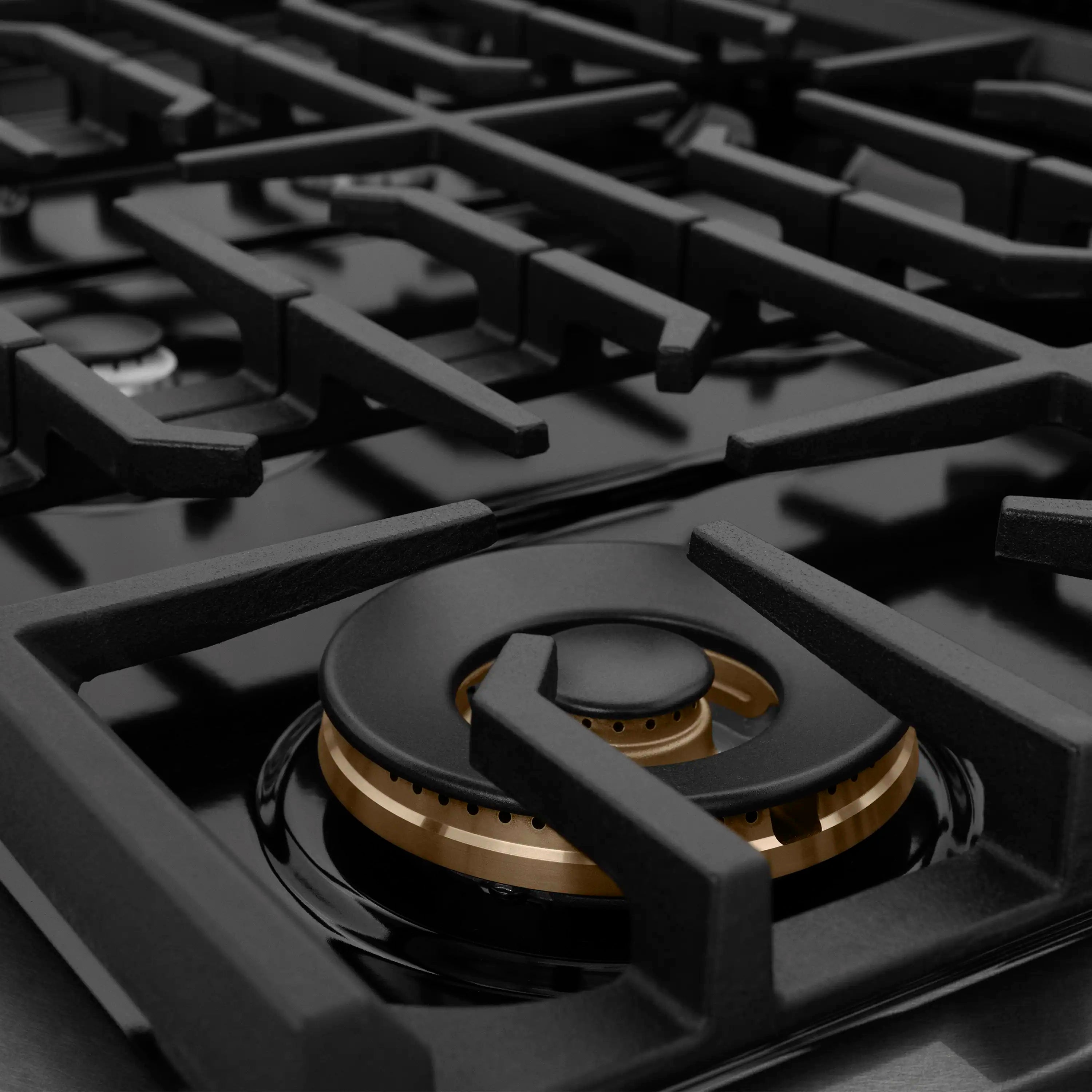 Gas cooktop burner grates with central round burner and black control knobs