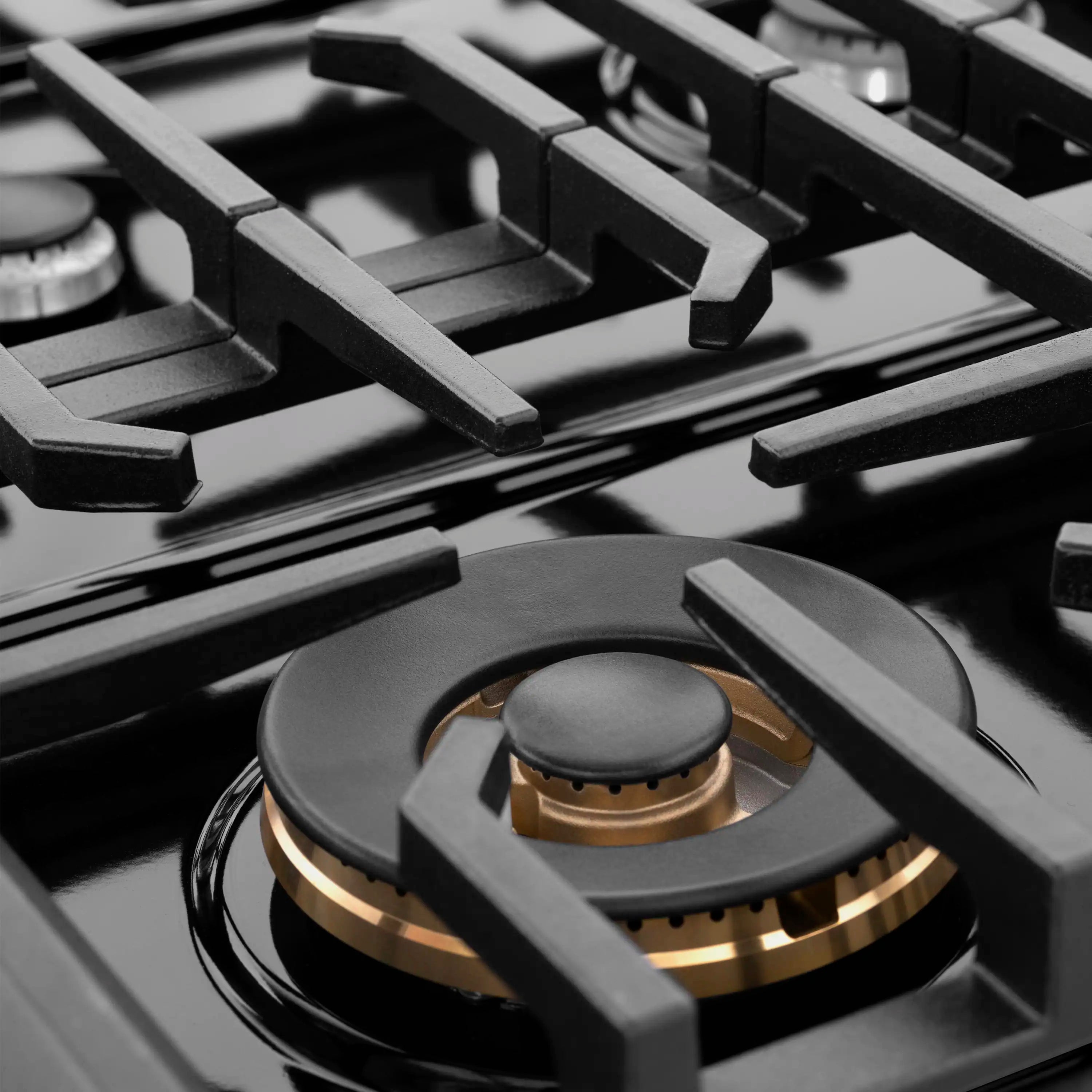 Black gas rangetop with cast grates and central burner with bronze cap
