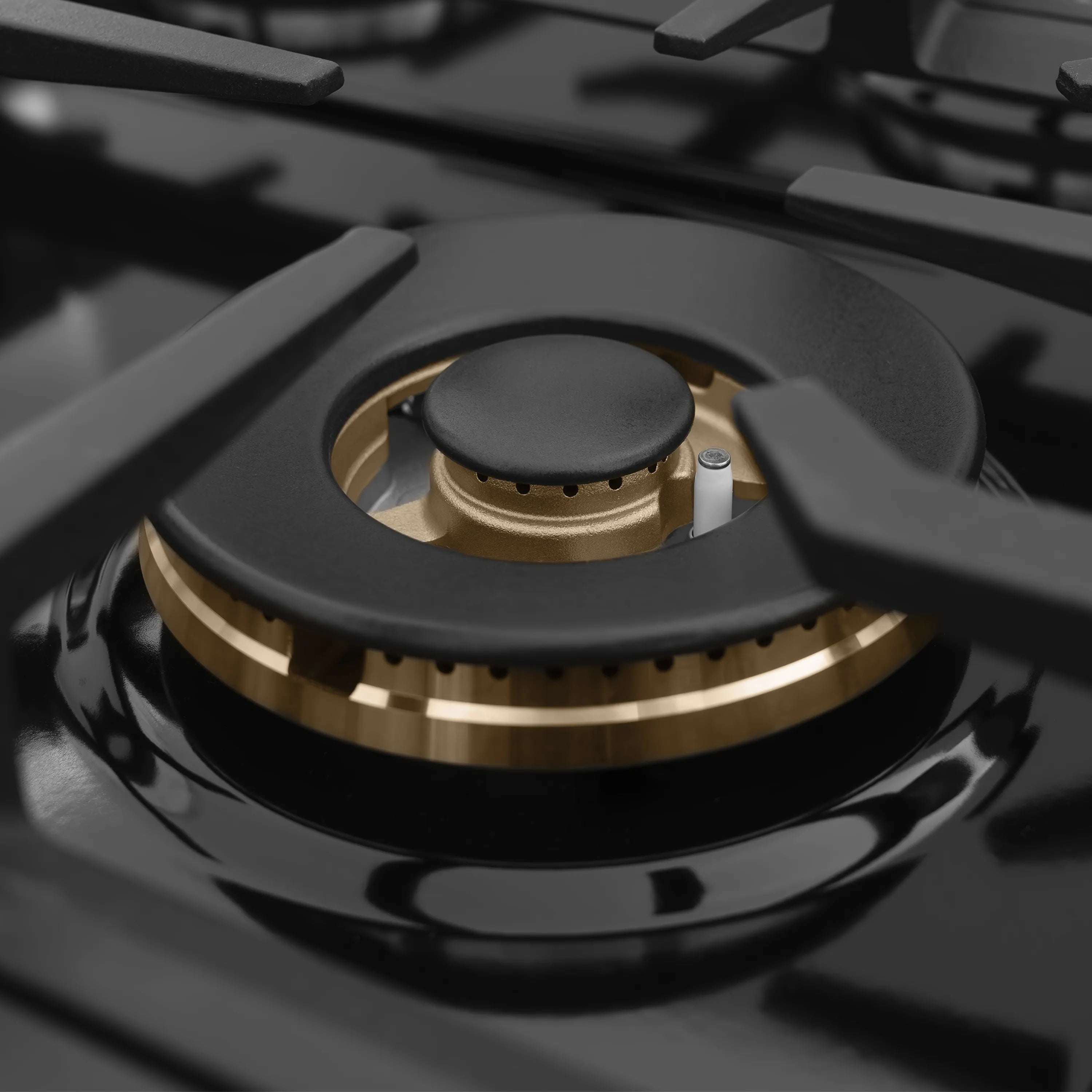 Close-up of black gas burner cap with brass ring and center burner opening