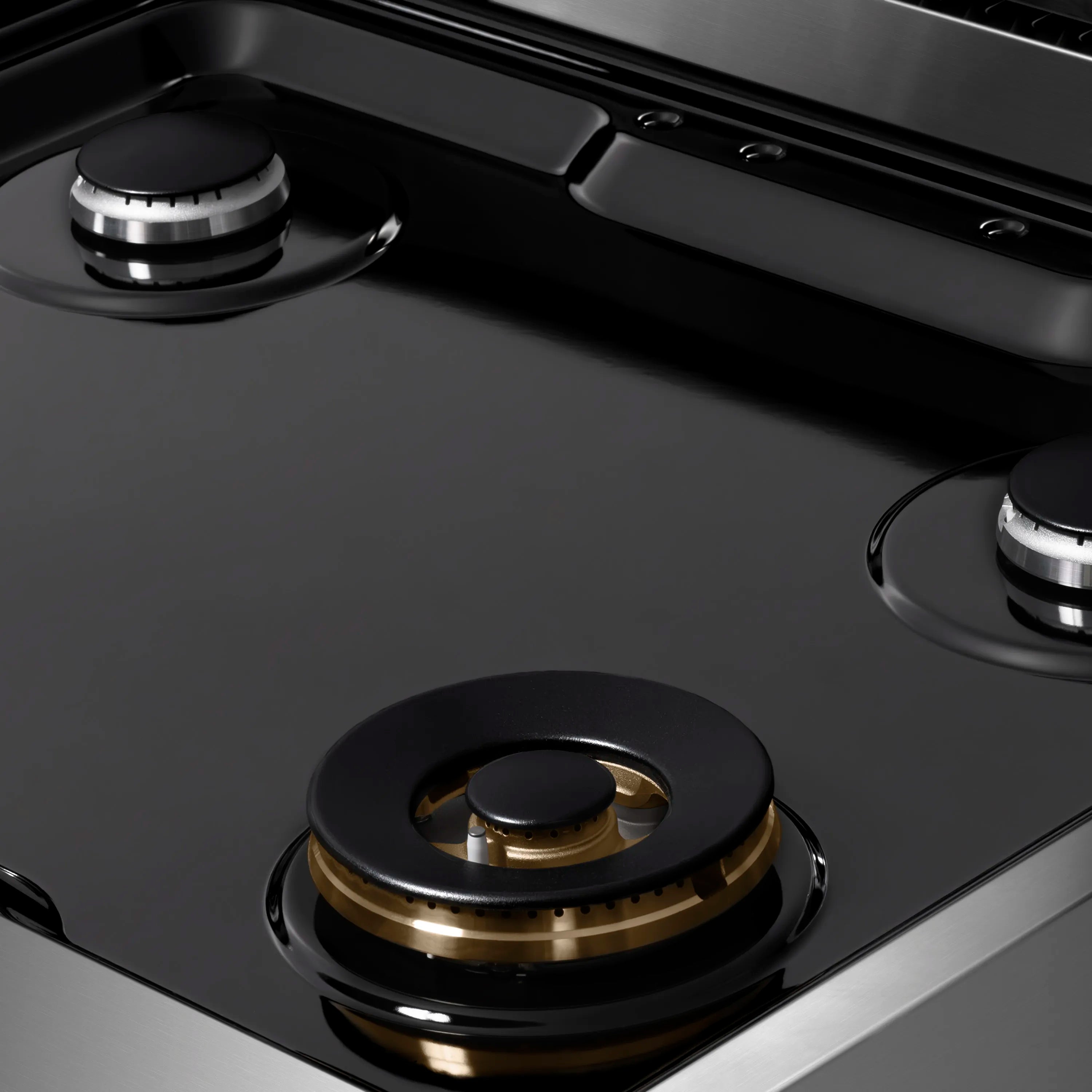 Black porcelain cooktop surface with circular burner caps and metal trim