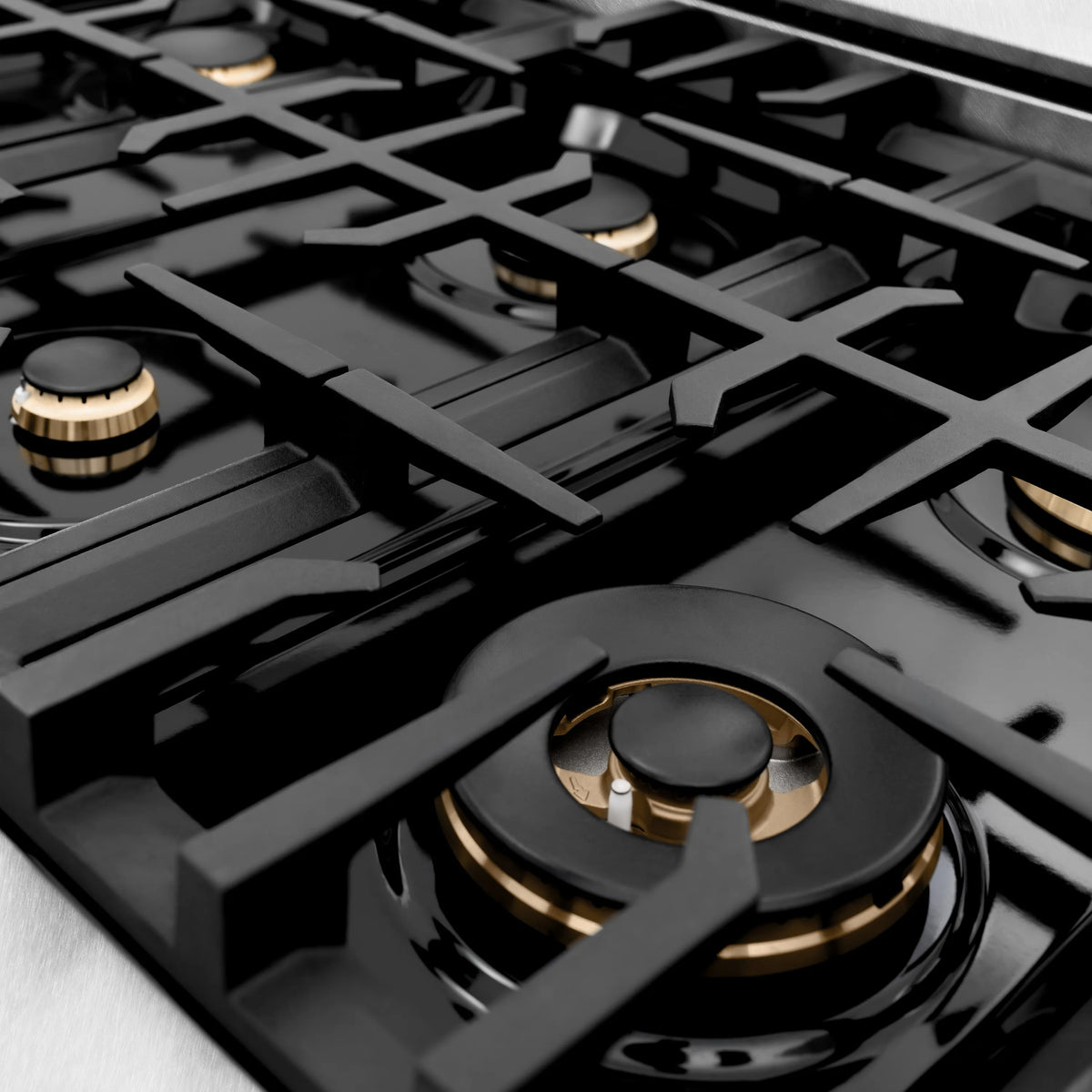 Gas stovetop with multiple burners and black cast-iron grates, brass accents