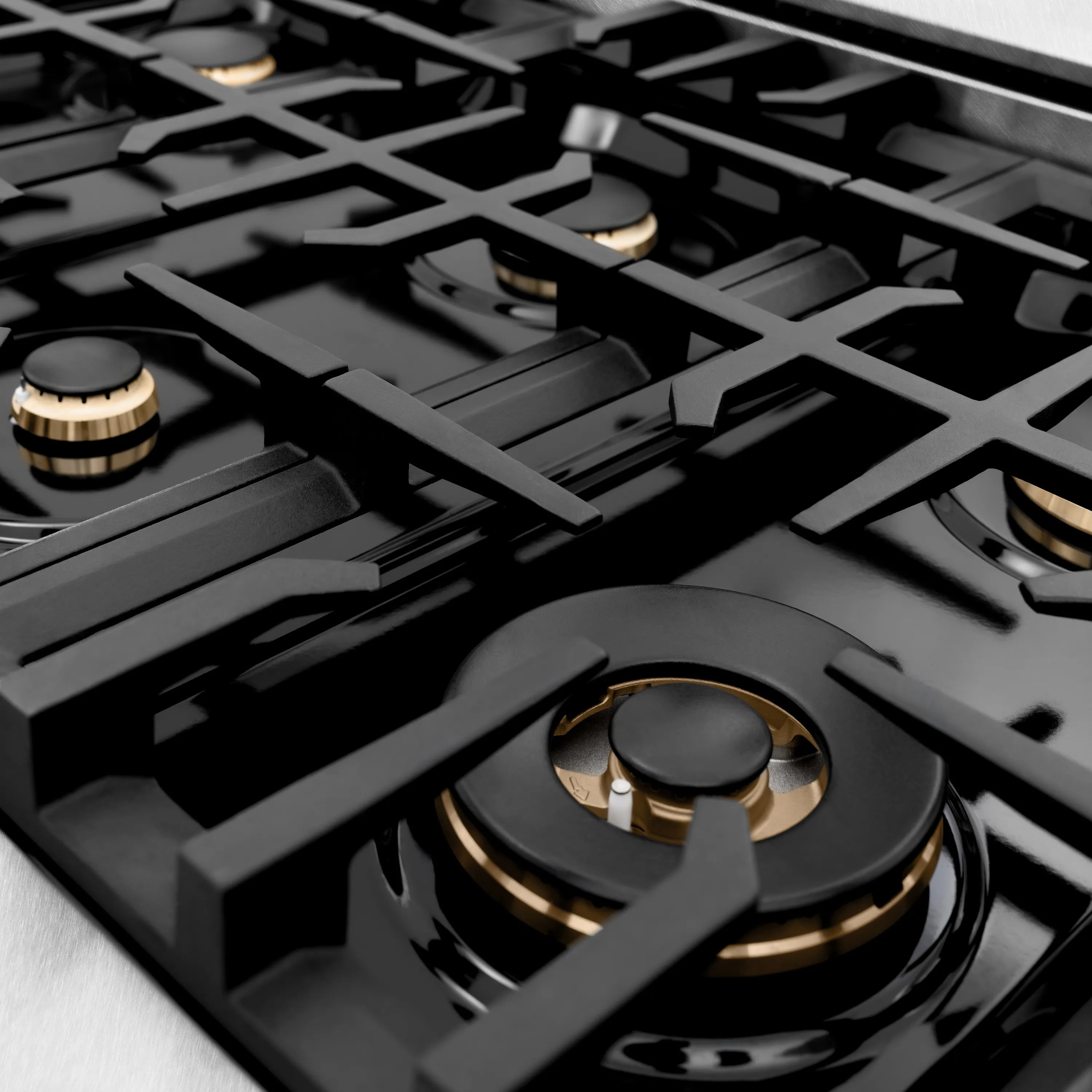 Multiple gas burners with black grates and brass-trim burner caps on cooktop