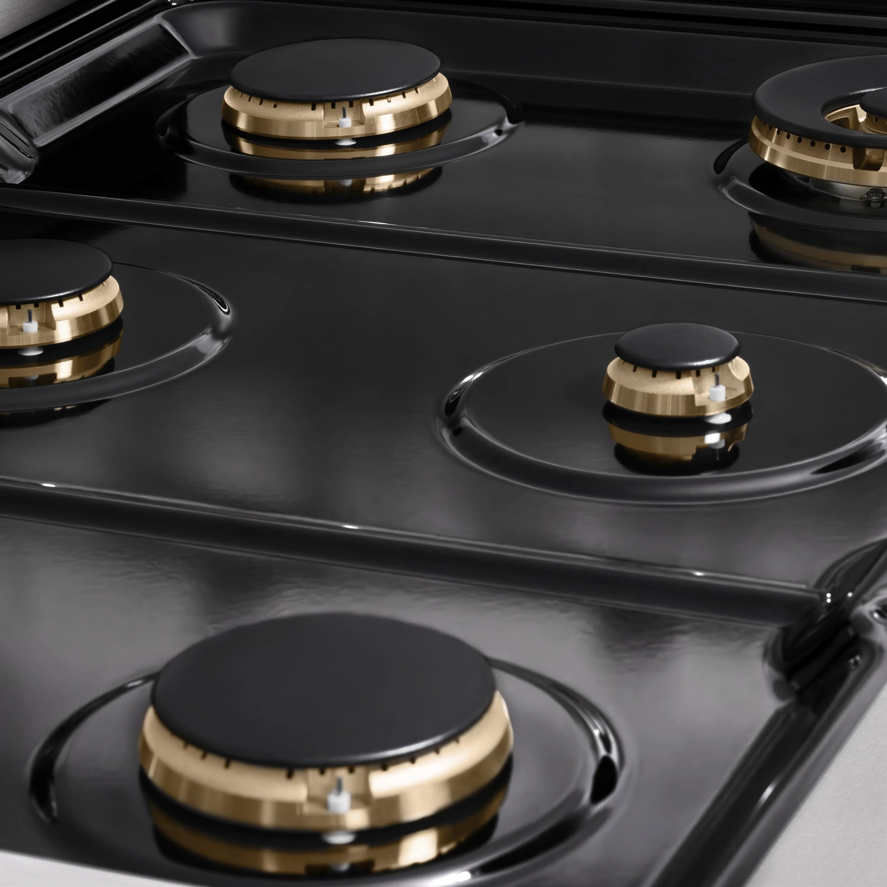 Glossy black gas cooktop with four visible burners and brass burner bases