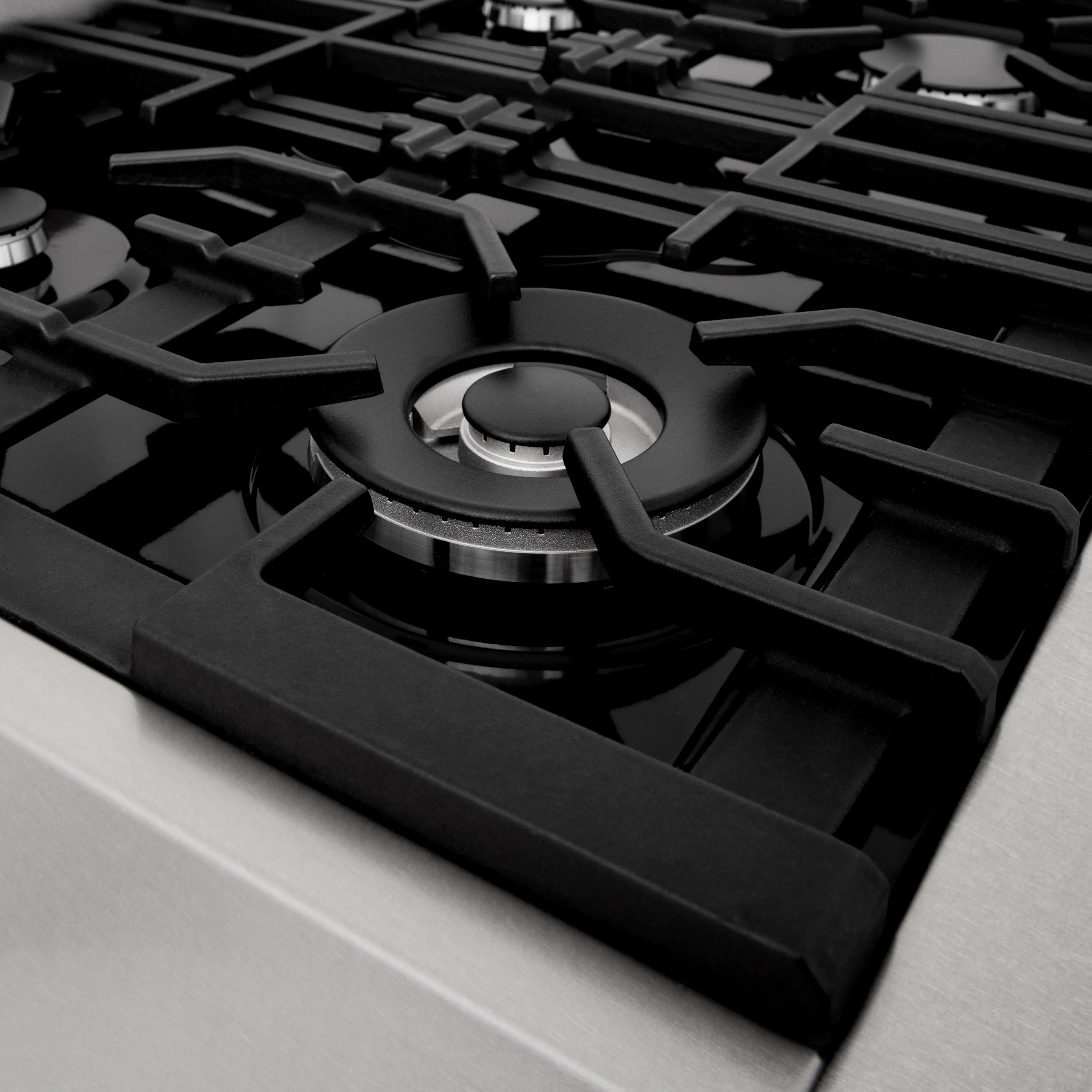 Gas stovetop burner with black cast-iron grate and round metal control cap