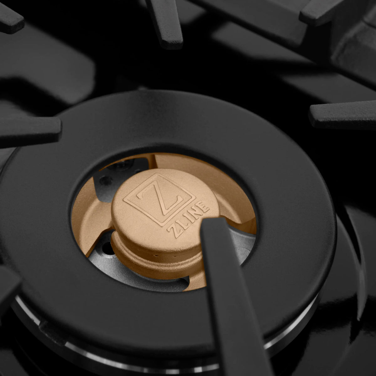 Single gas burner on black cooktop with brass cap and black burner ring