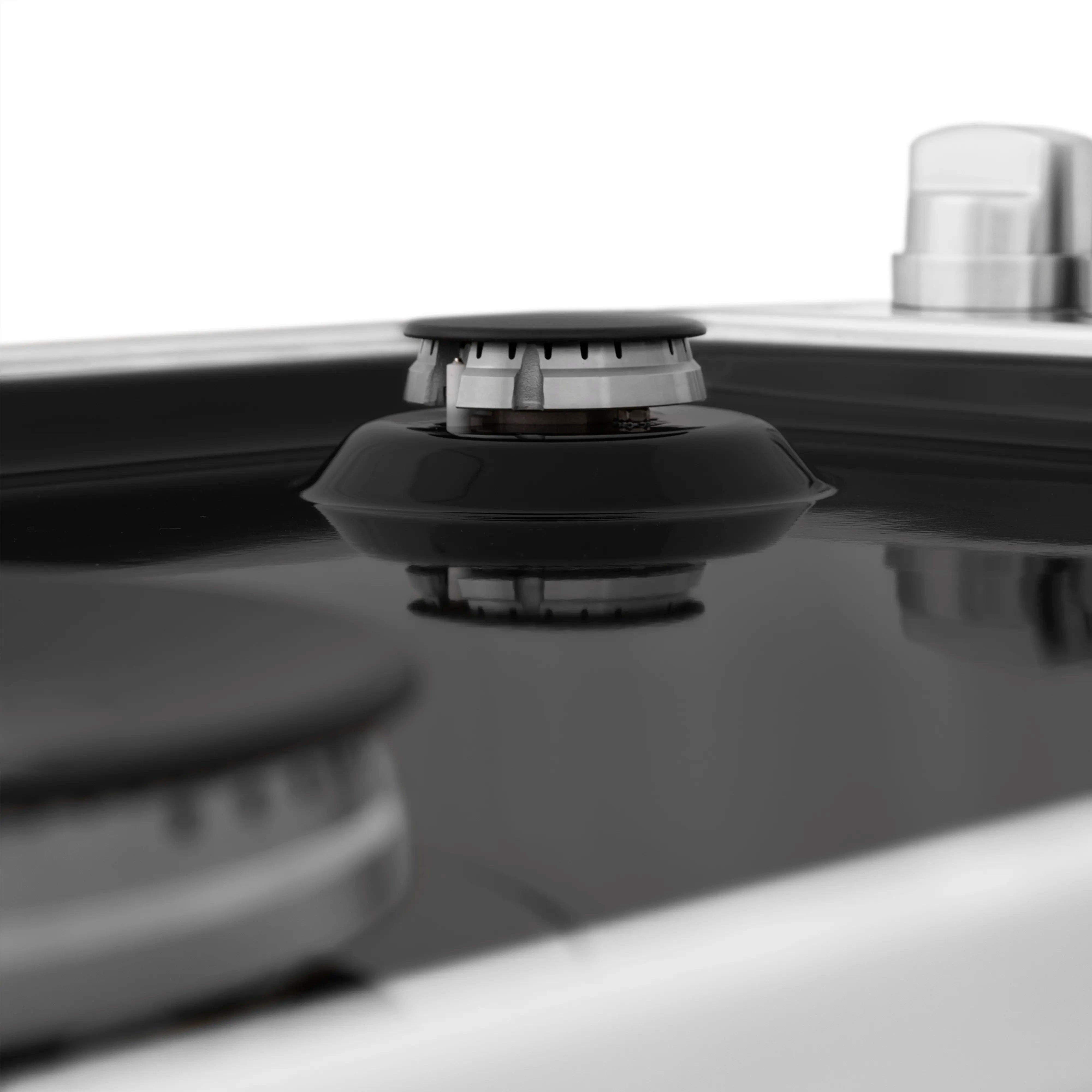 Black gas burner cap on a black porcelain cooktop surface