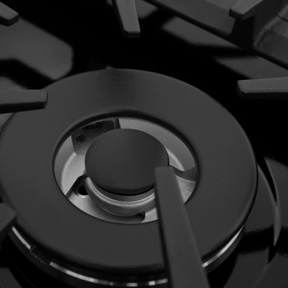 Round black gas burner with grate and burner cap on black cooktop