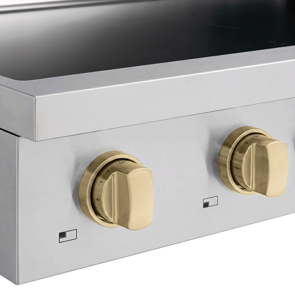 Close-up of champagne bronze induction cooktop knobs on stainless steel control panel