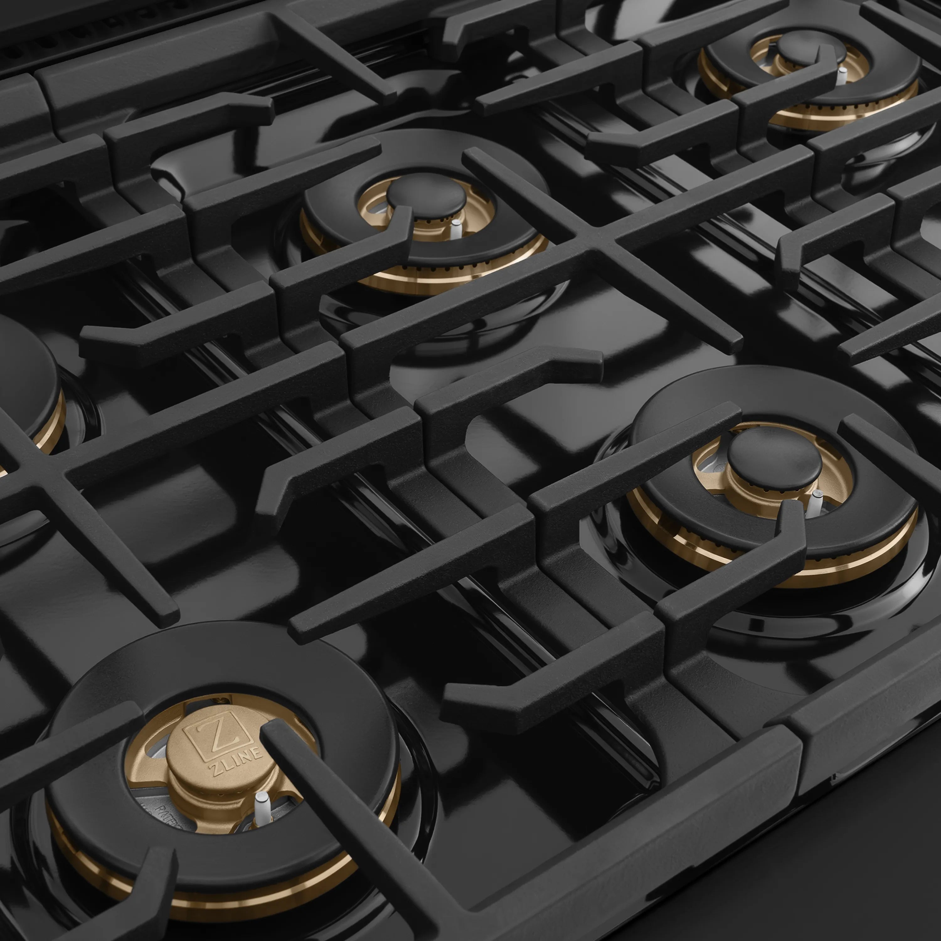 Black gas cooktop with brass-capped burners on cast iron grates