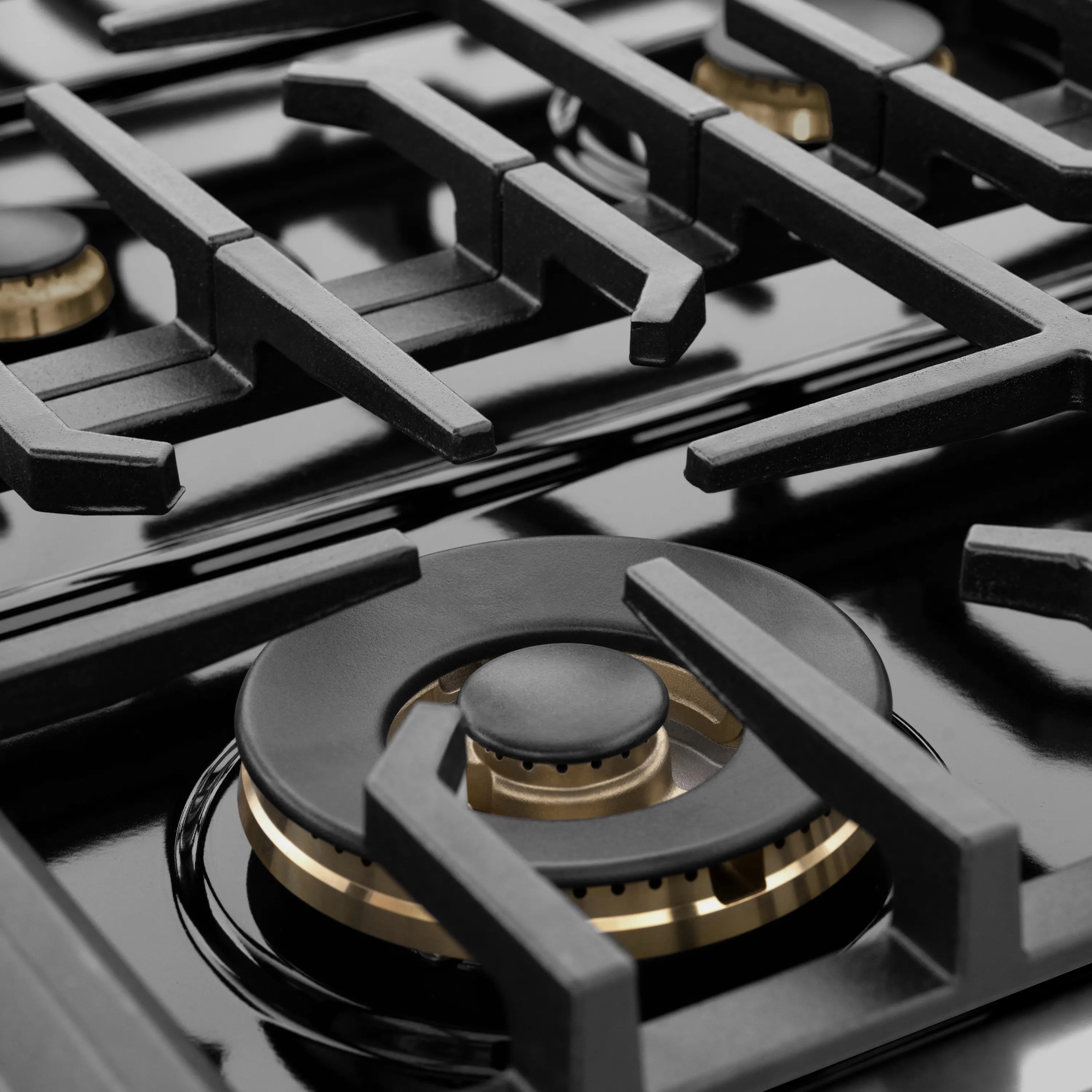 Black cast-iron grates and brass burner cap on gas cooktop