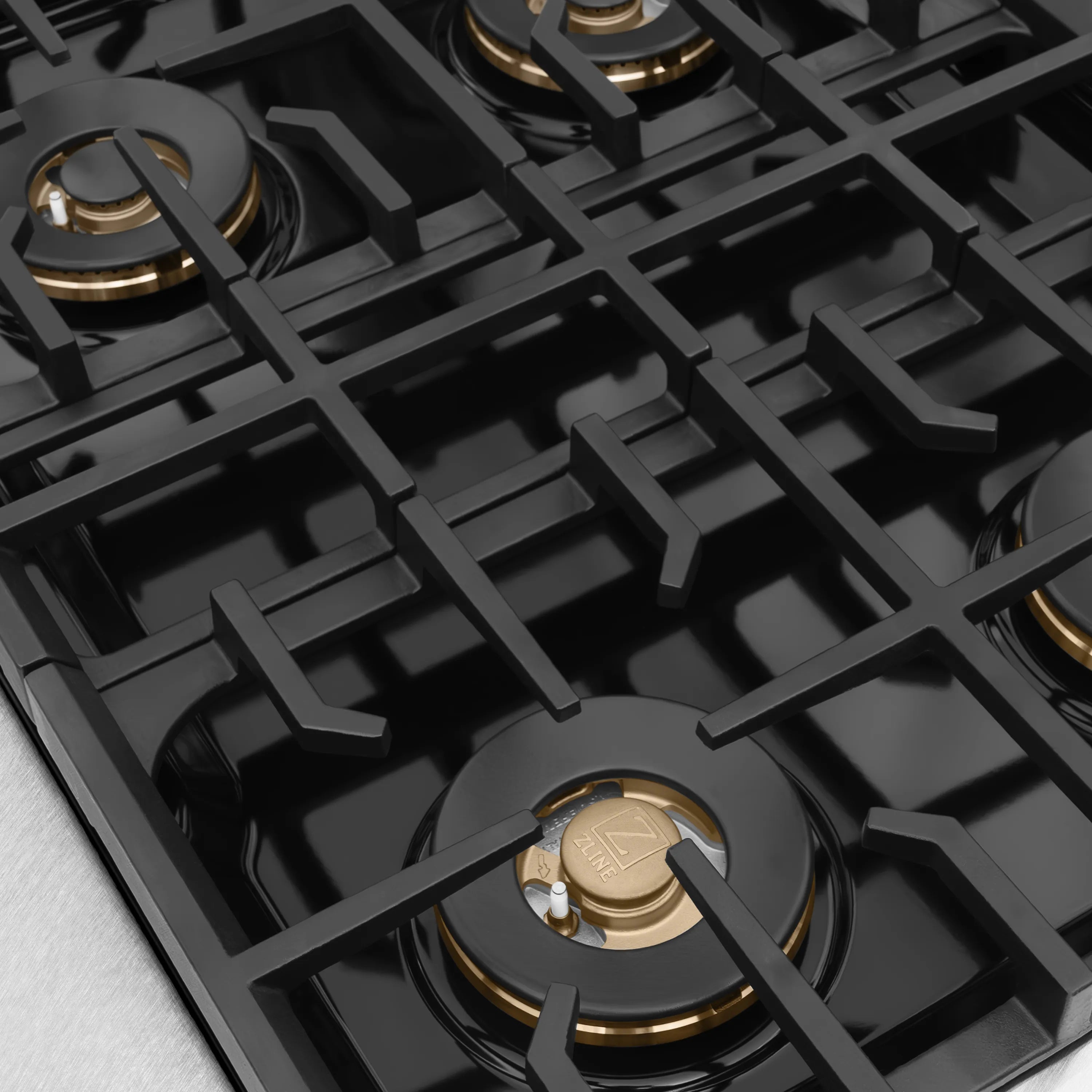 Black gas cooktop with cast grates and brass burner caps