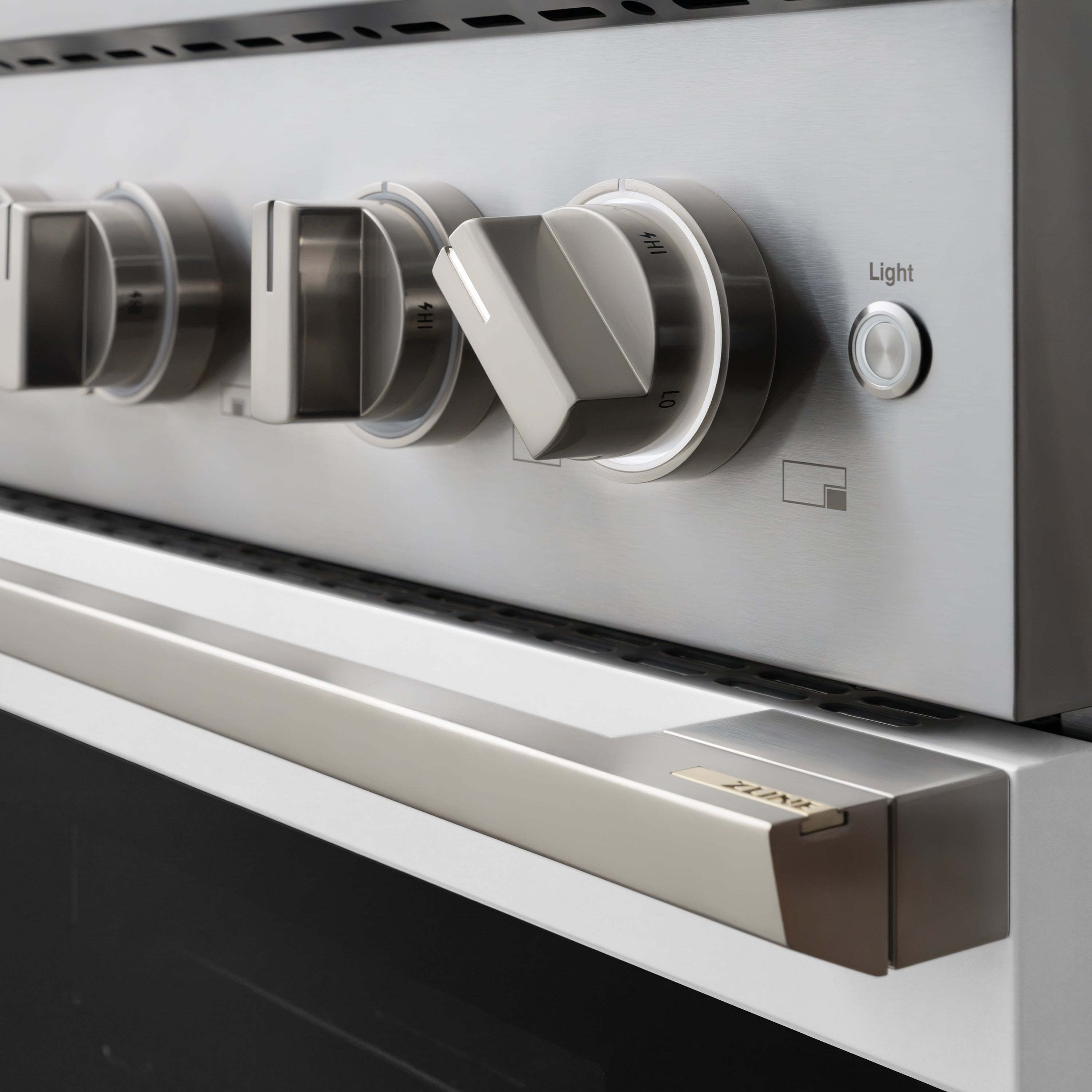 Stainless steel oven control panel with large knobs and Light button