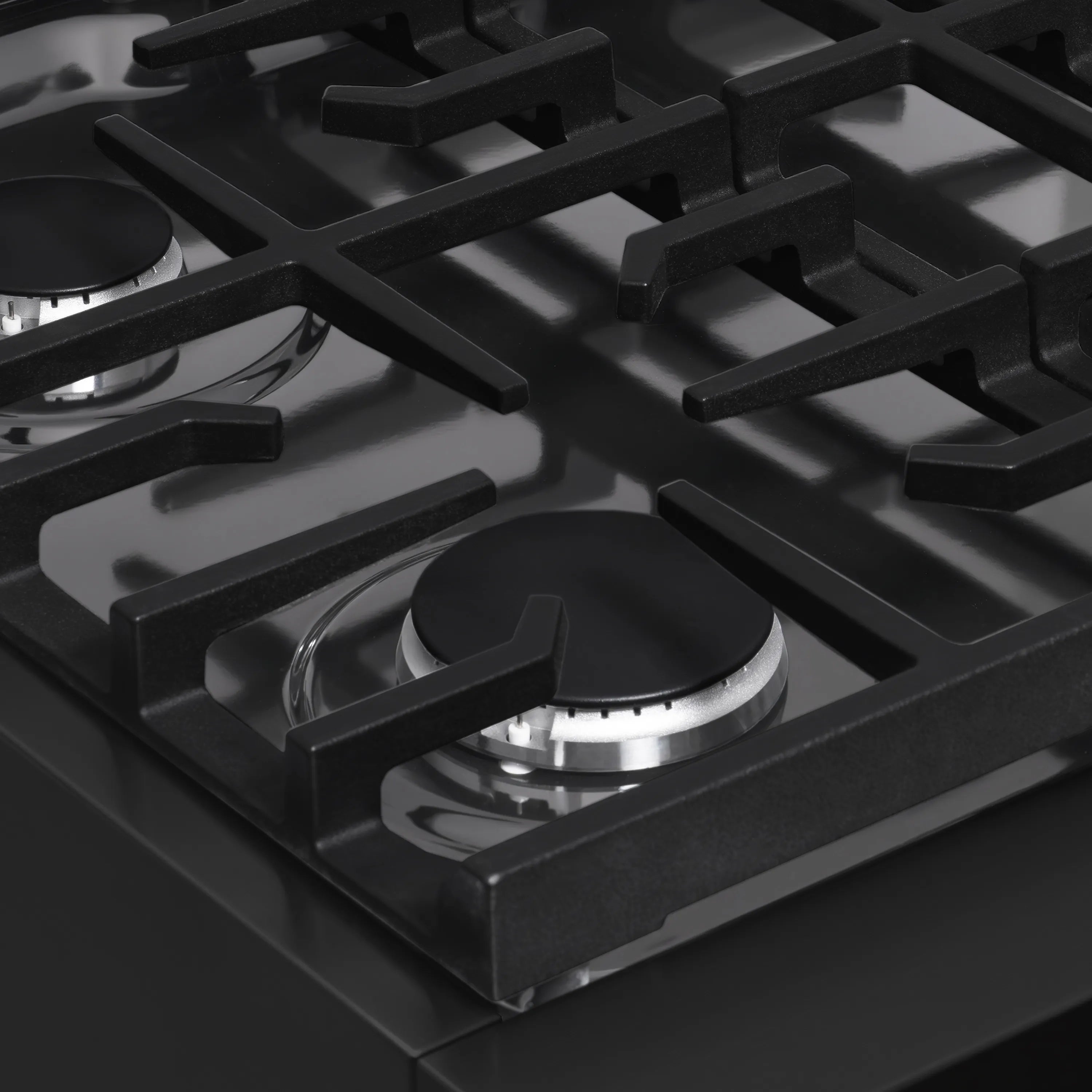 Black gas range cooktop burner head under cast-iron grate
