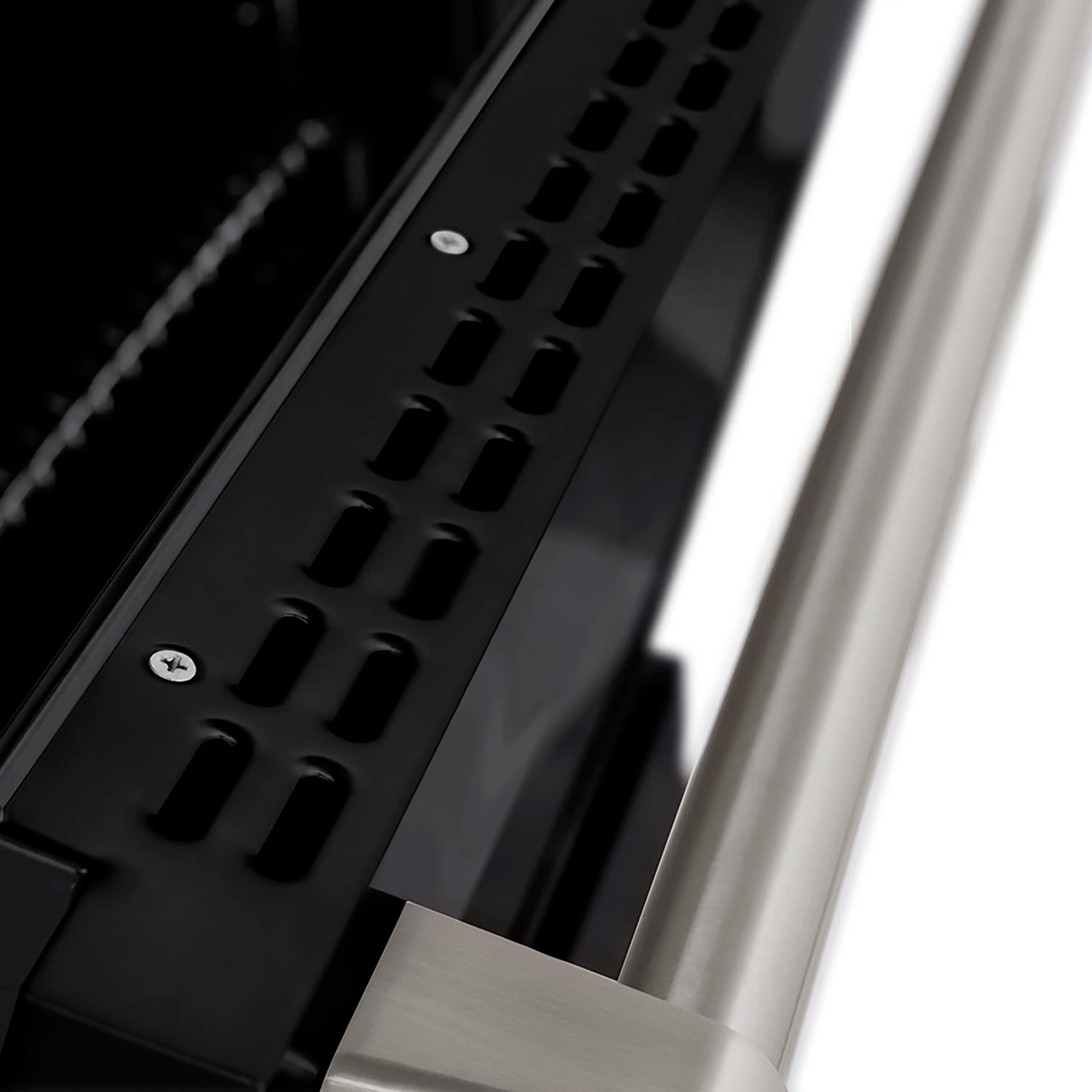 Side view of black cooktop grates beside satin stainless control edge