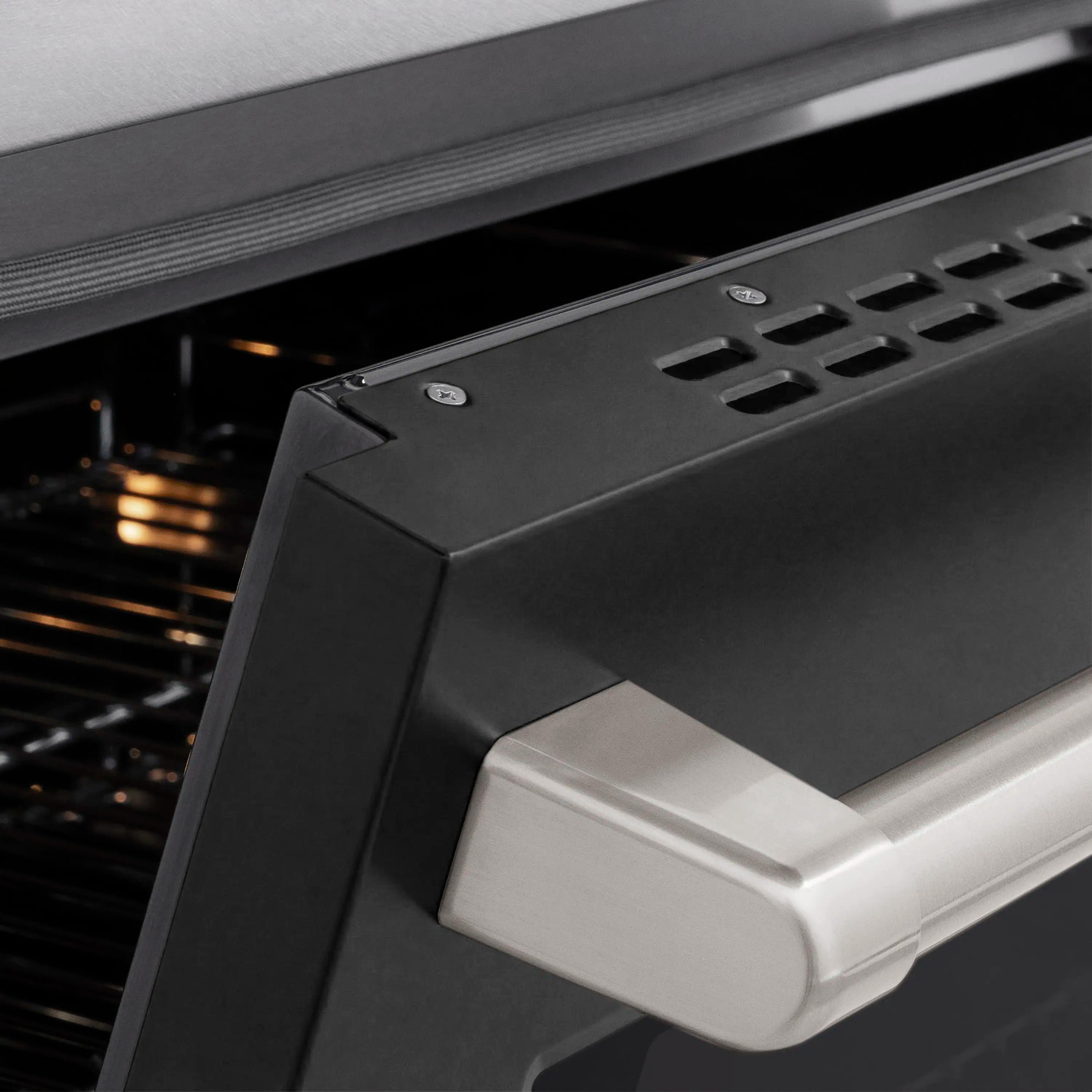Oven door handle and top vent on satin stainless induction range with black interior
