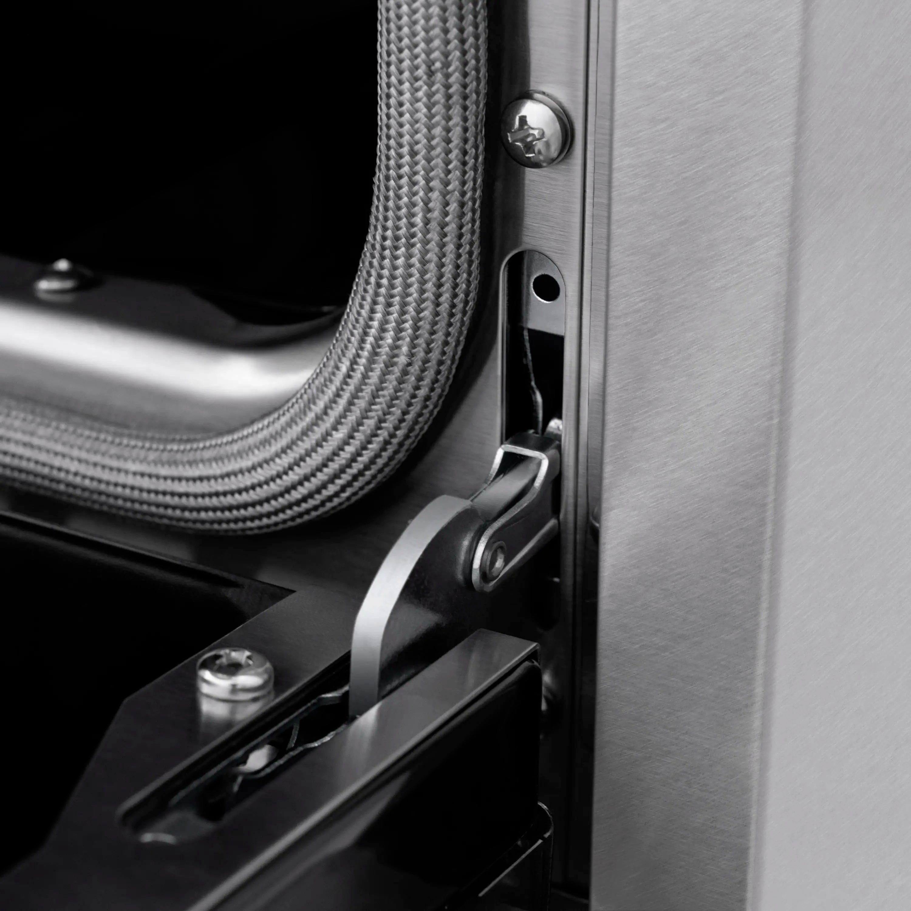 Stainless oven door latch and curved handle detail with flexible cable nearby