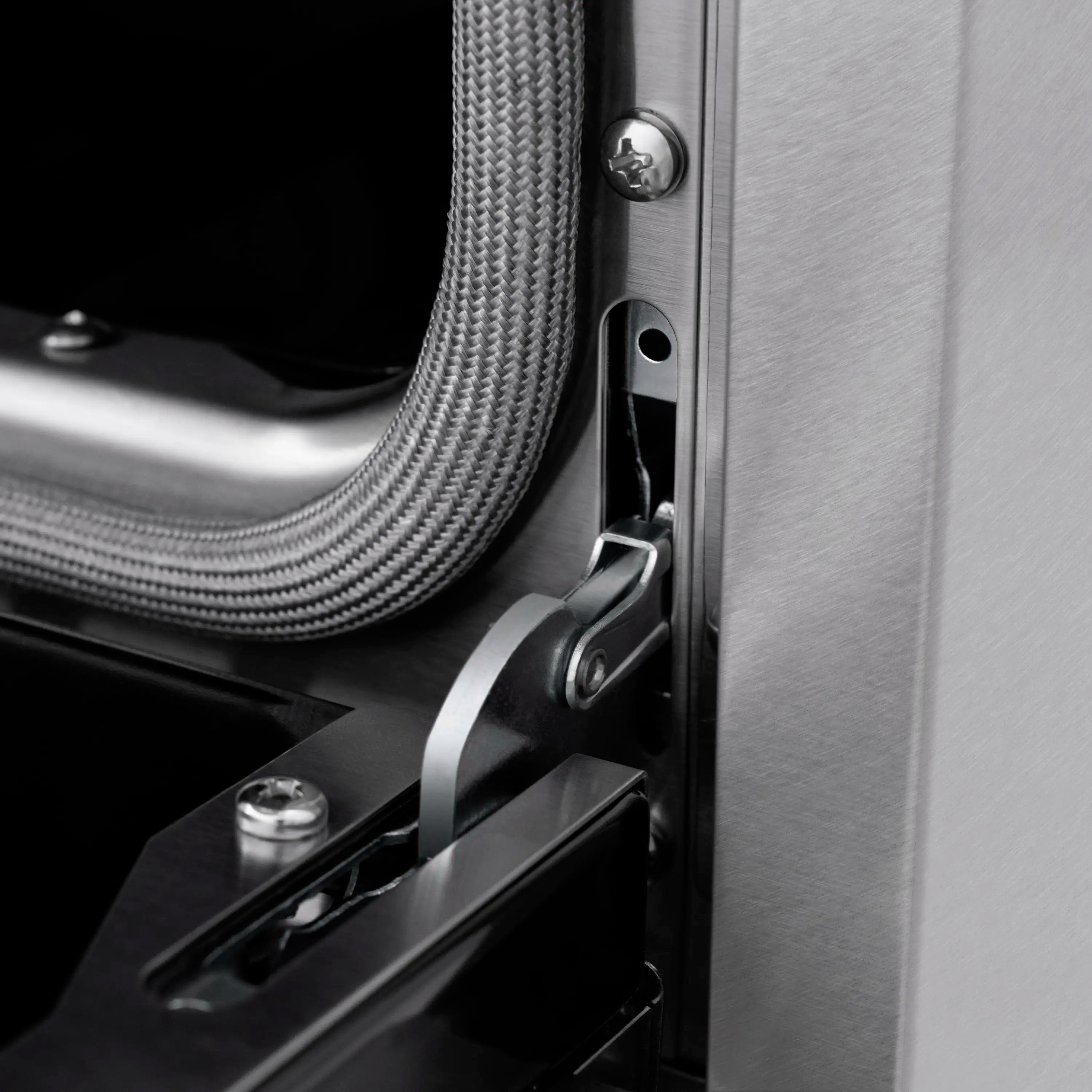 Stainless steel side panel with latch and braided cable near oven opening