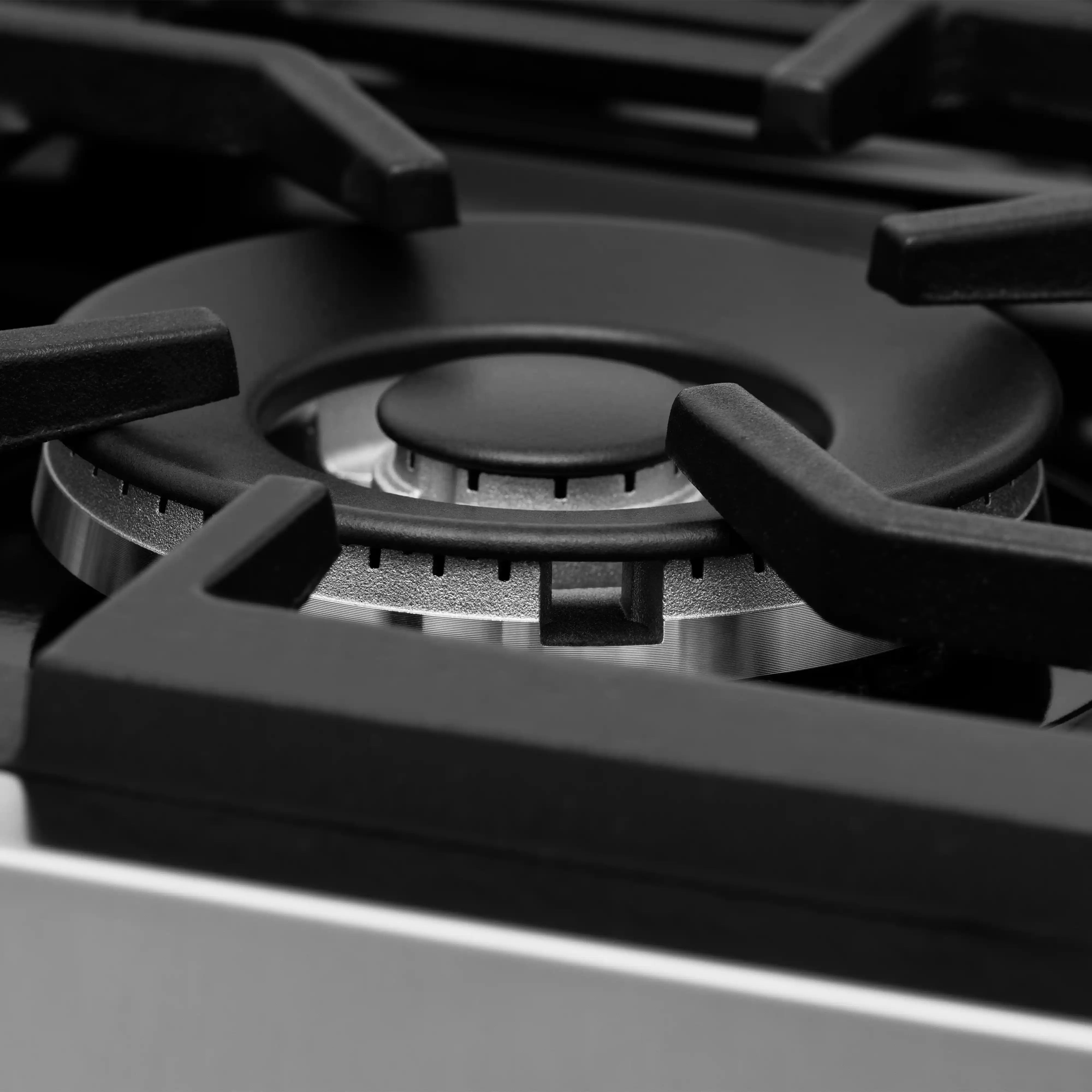 Close-up of gas burner grates on a stainless dual fuel range cooktop.