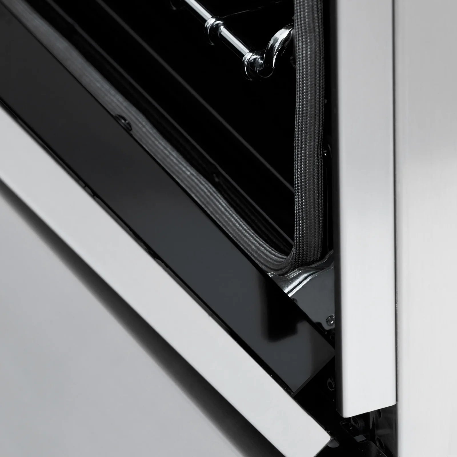 Oven door edge with inner seal and metal frame, close-up