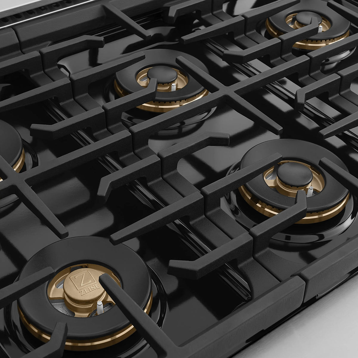 Black multi-burner cooktop with cast grates and brass-toned burner caps