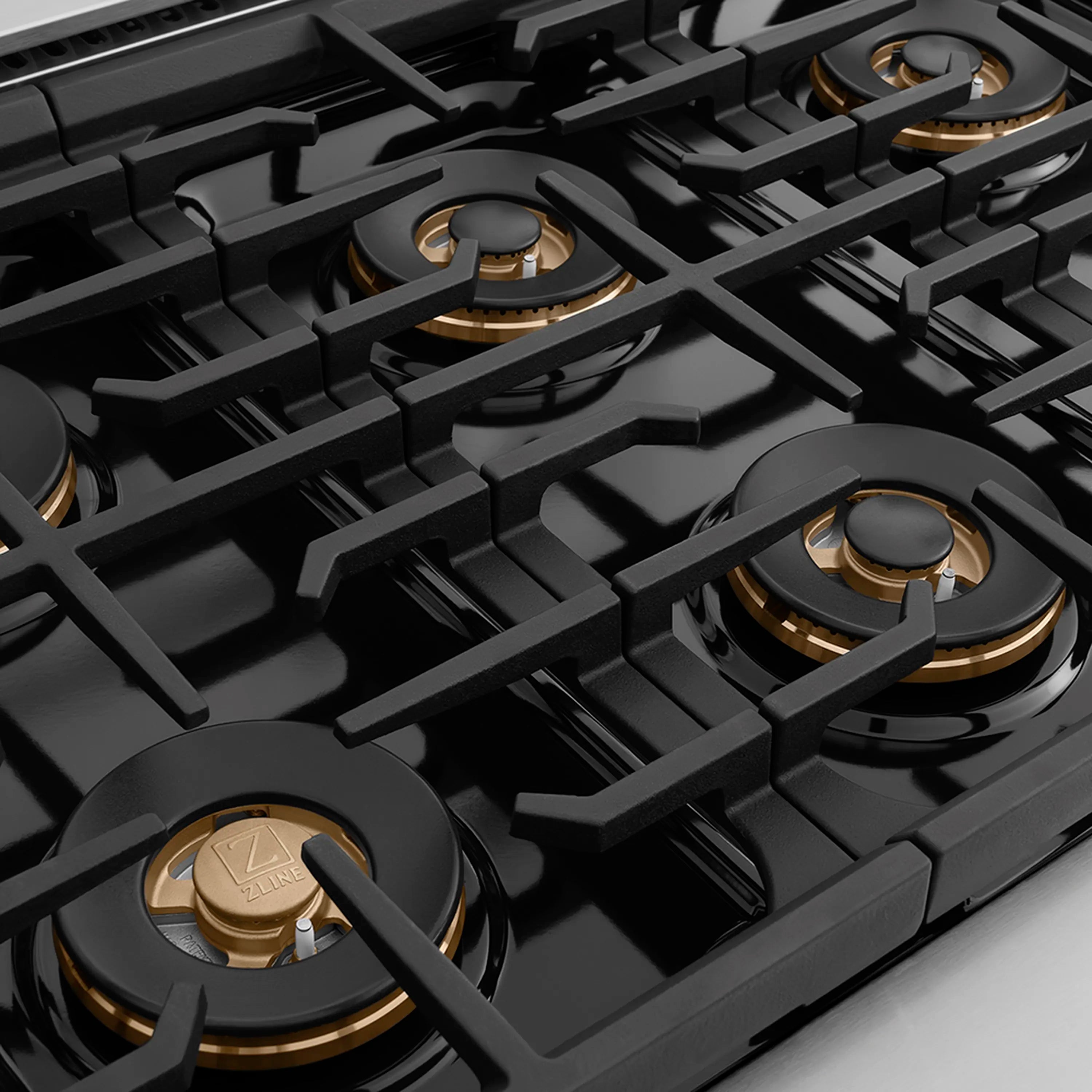 Stainless steel gas cooktop with black cast-iron grates and gold burner rings
