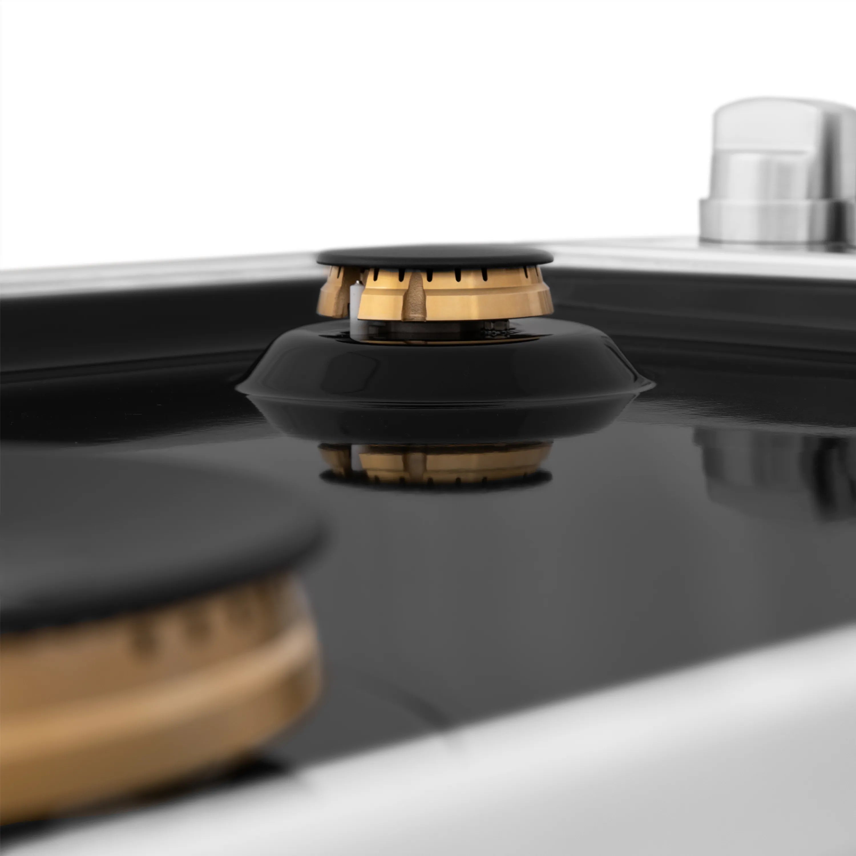 Black porcelain gas cooktop with brass burner cap centered on the cooktop surface