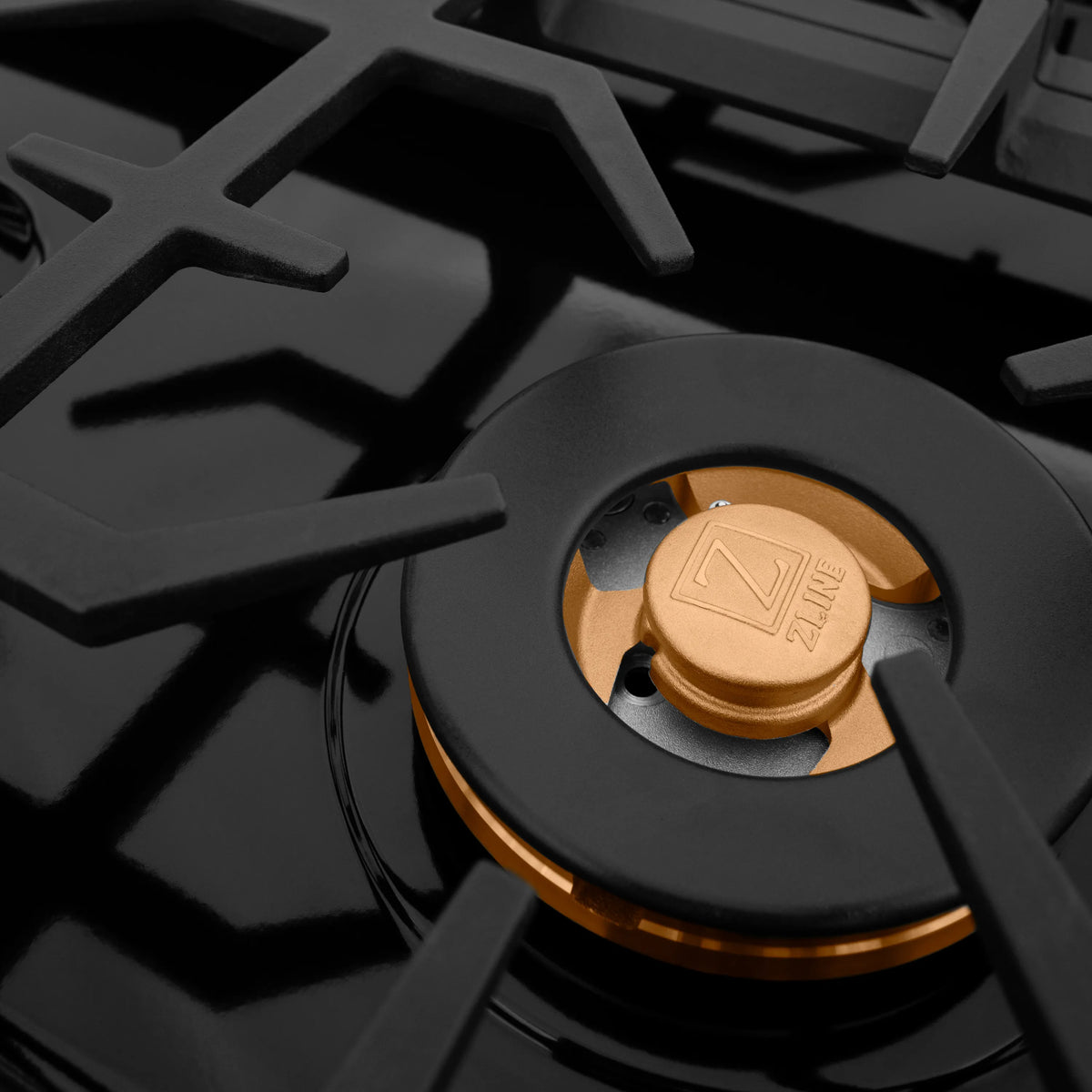 Close-up of black gas burner head with brass insert and ZLINE markings