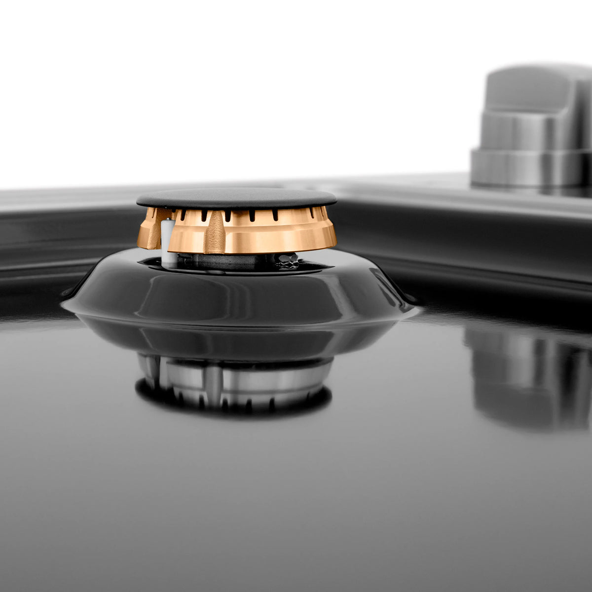 Black porcelain gas burner with brass cap and ring, with control knob in background