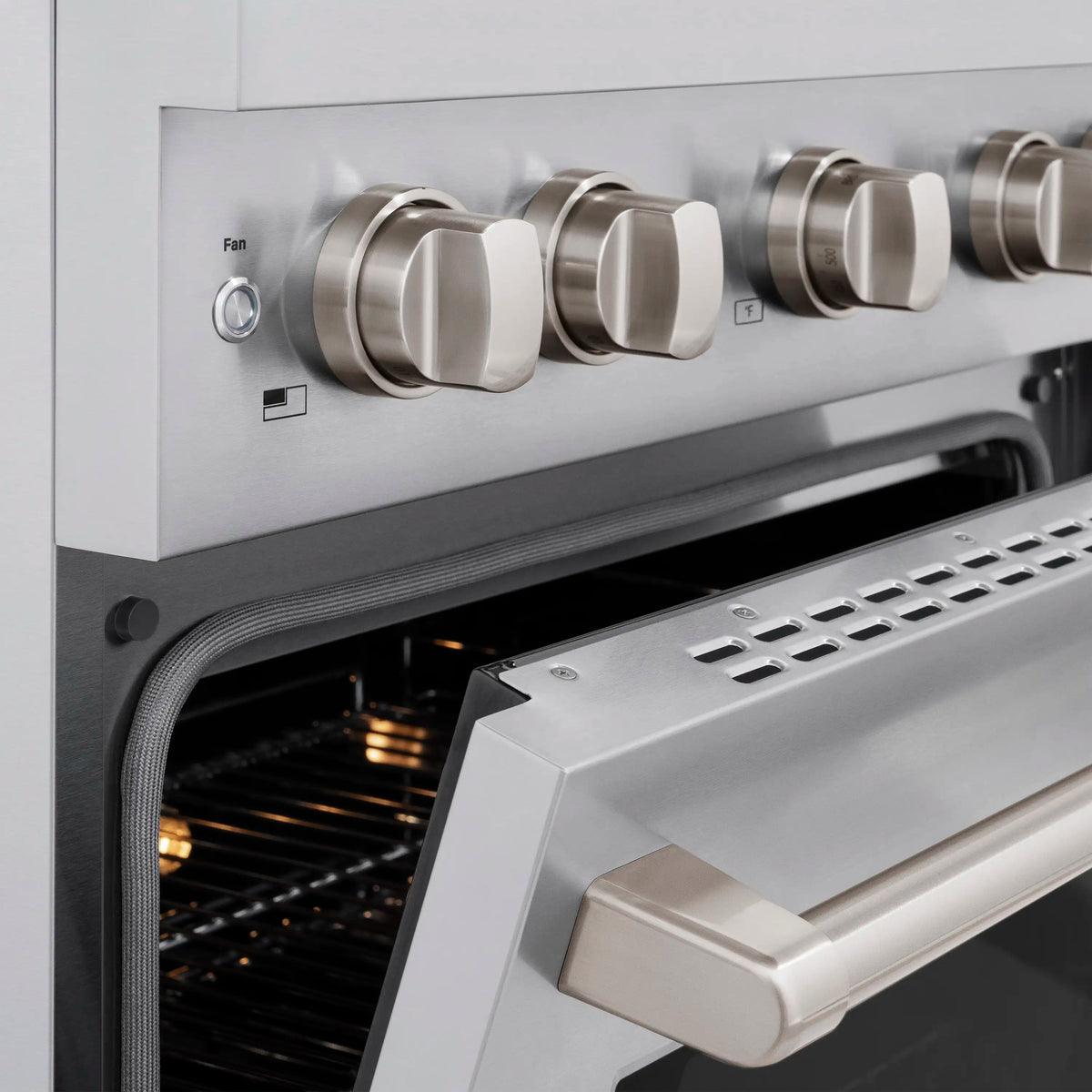 Stainless steel range control knobs and open oven door, with fan switch