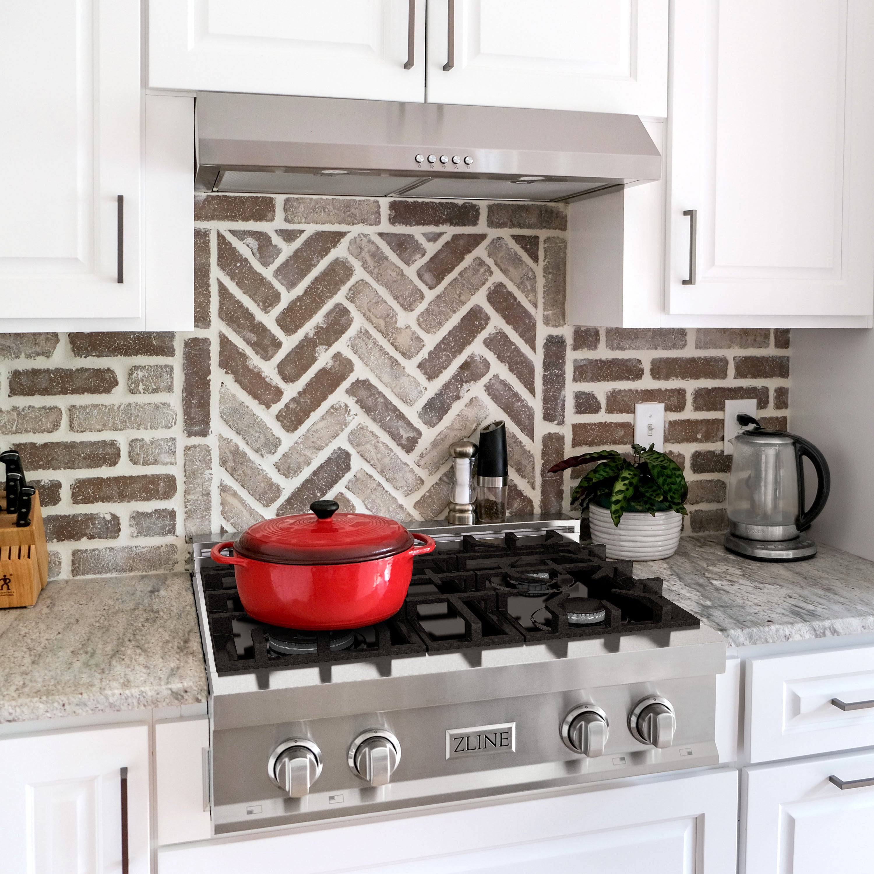 Stainless steel gas rangetop with black grates and matching over-the-range hood