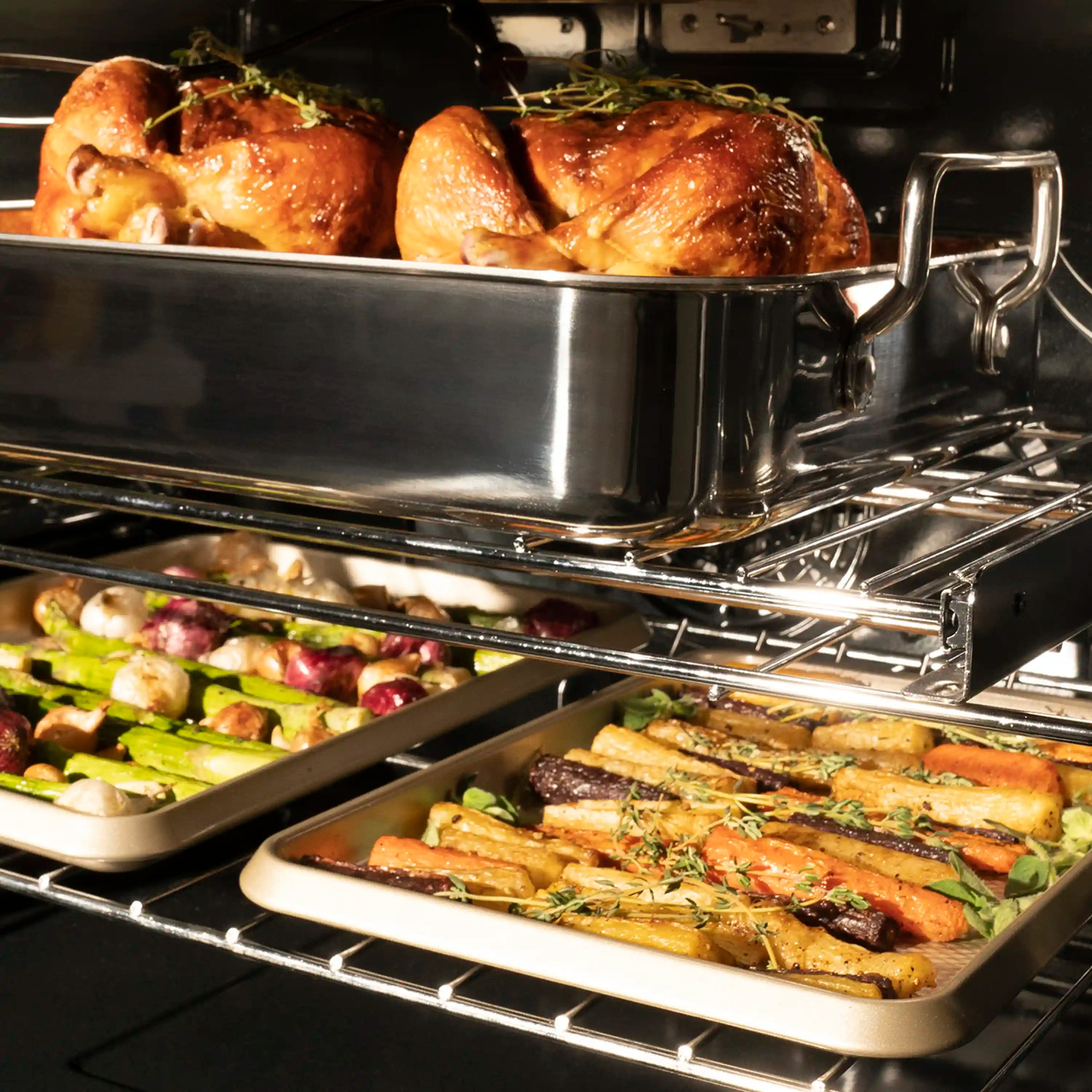 Stainless steel single wall oven with rack holding roasted chicken and vegetables