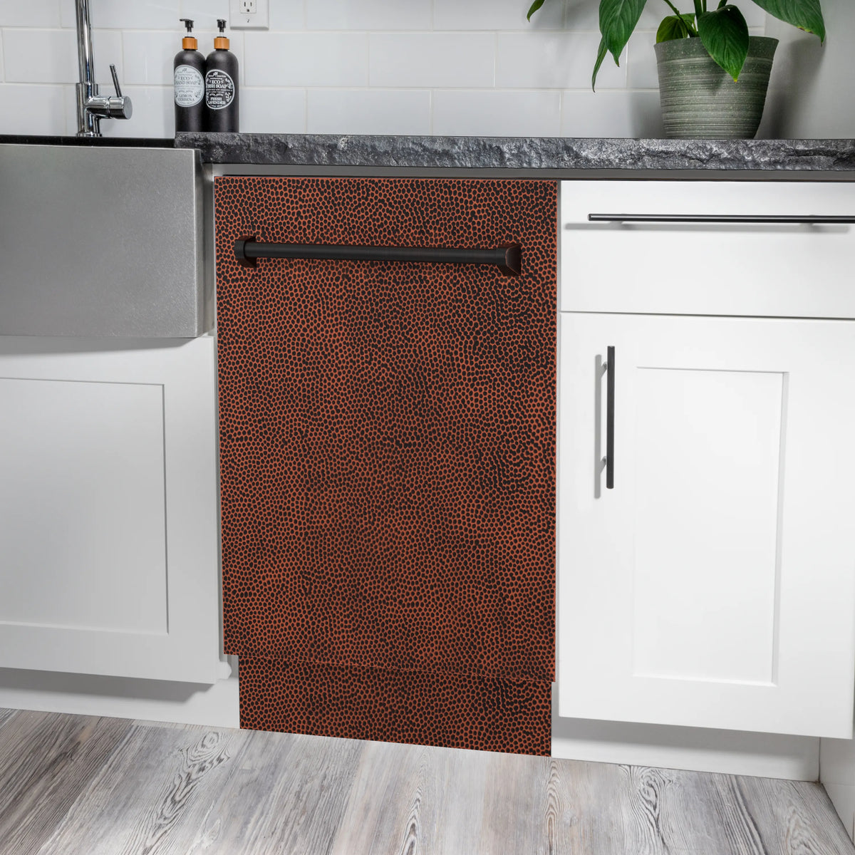 Hammered copper dishwasher door in a kitchen cabinet opening