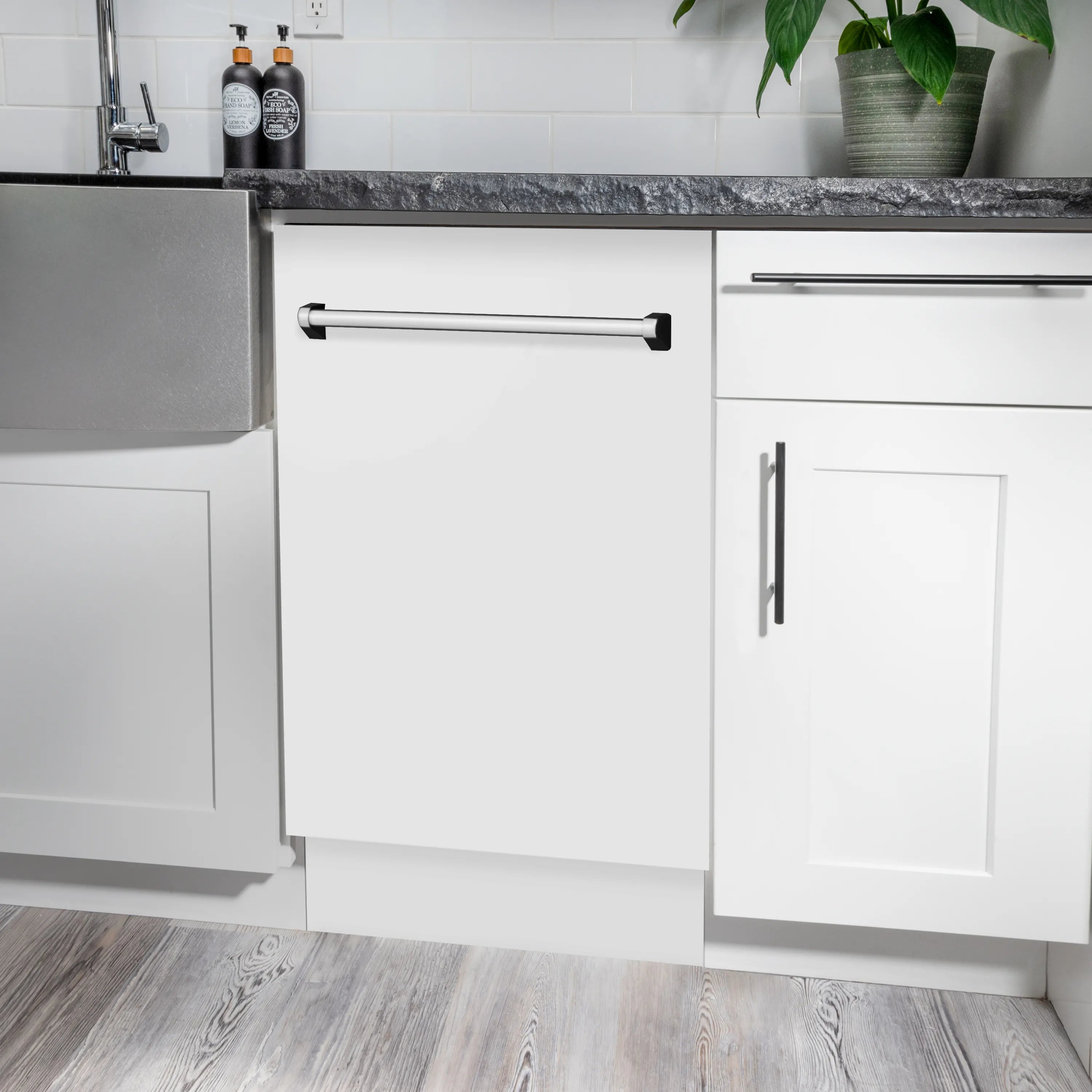White dishwasher with stainless pull handle installed in a kitchen cabinet