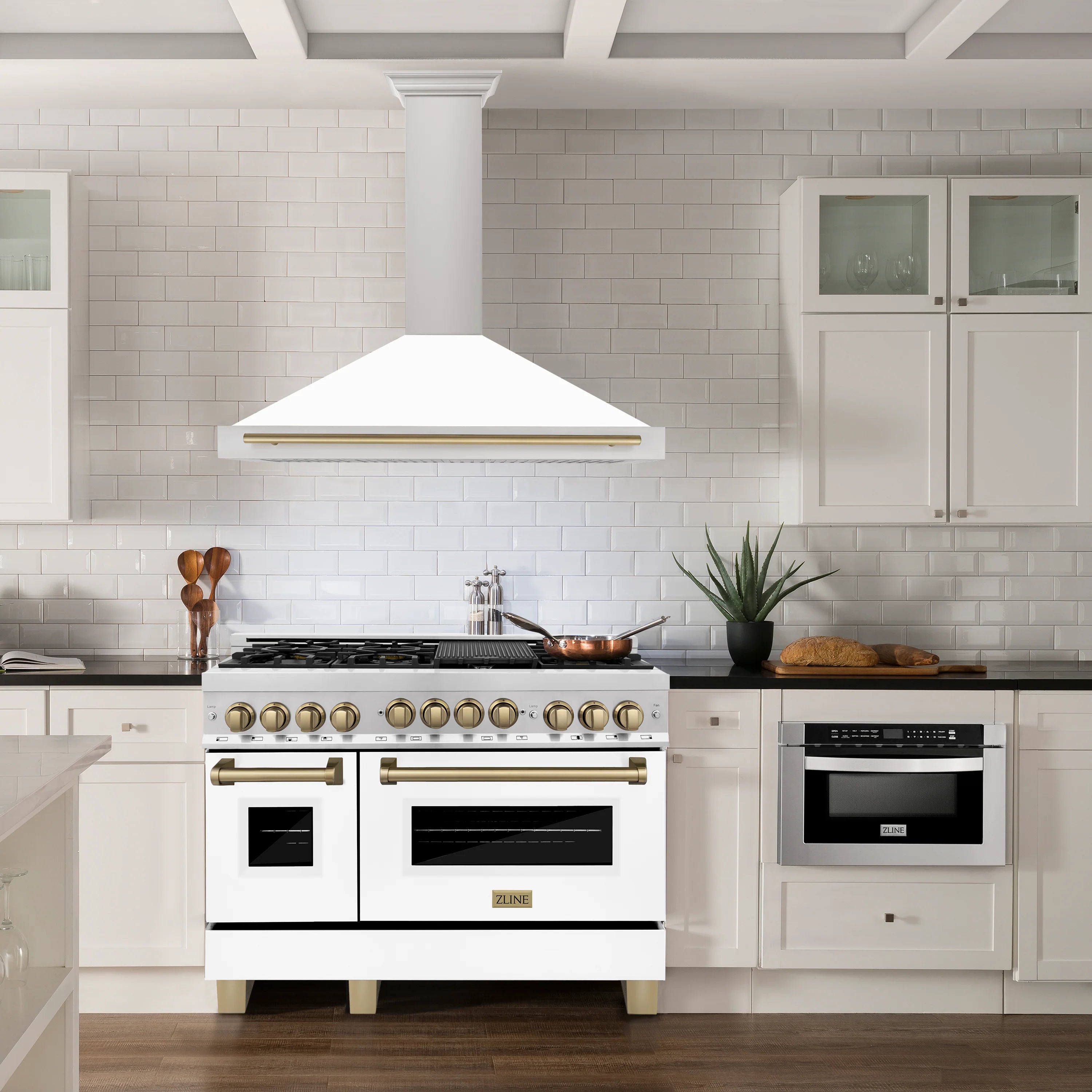 White wall-mounted range hood over cooktop with bronze accent bar and vent grille