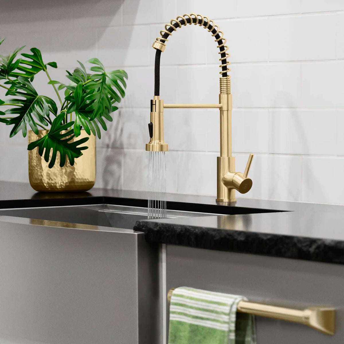 Champagne bronze pull-down kitchen faucet with black spray line and coiled spring