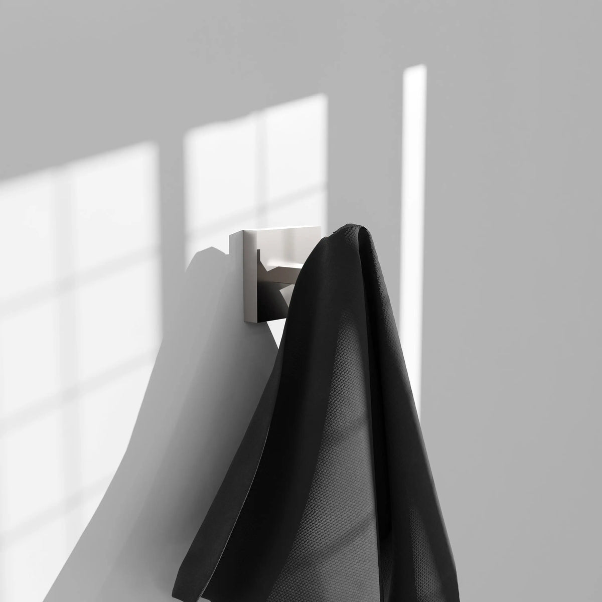 Brushed nickel towel hook with black towel hanging from curved arm
