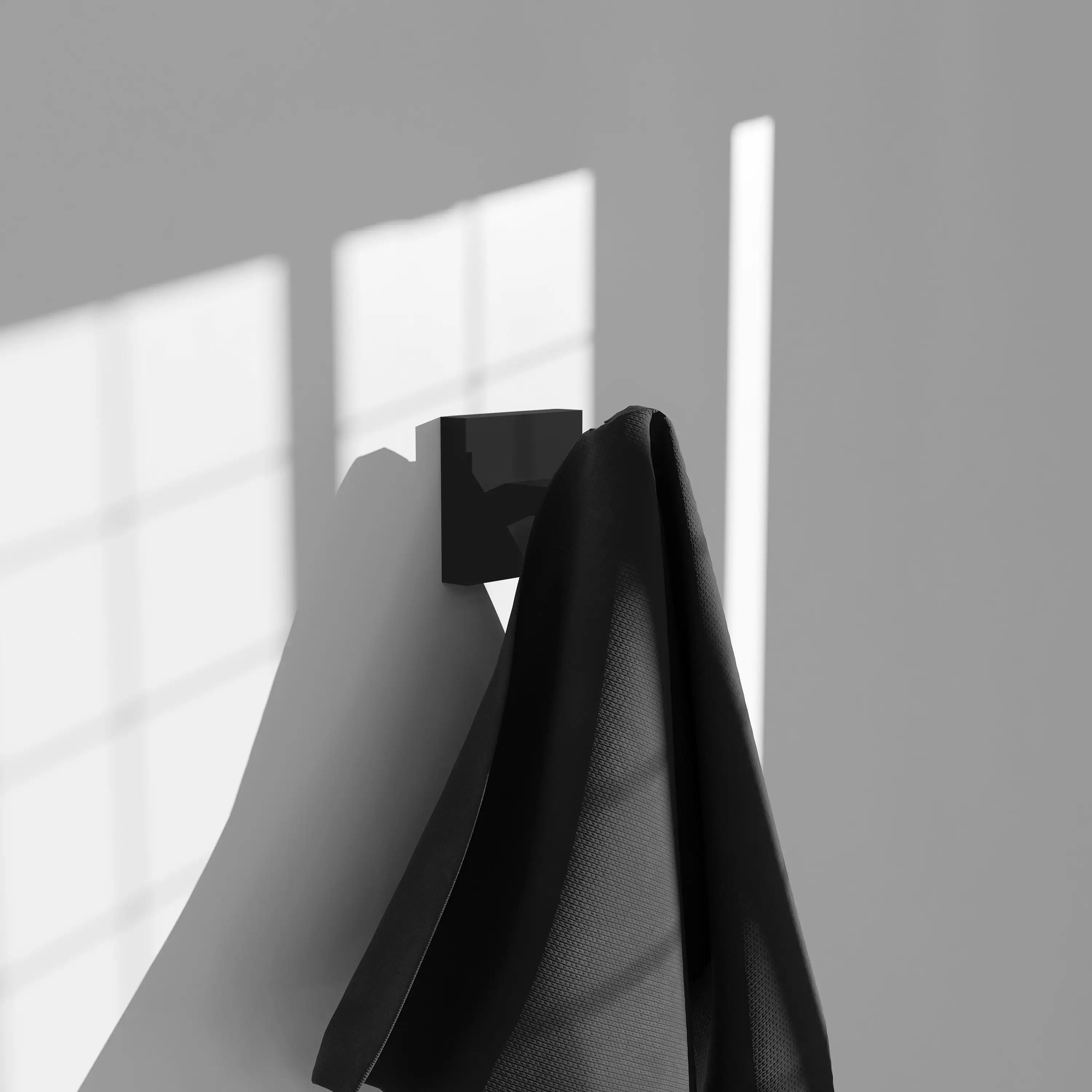 Matte black square towel hook holding a folded dark towel