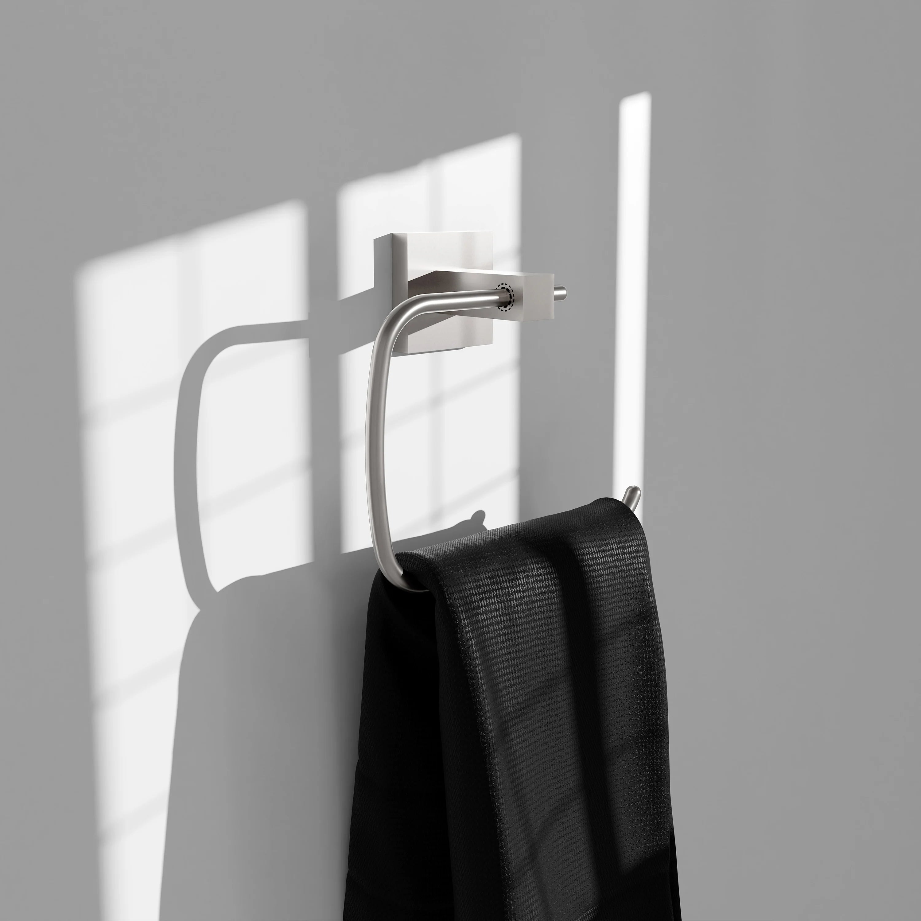 Brushed nickel towel ring with black towel hanging from curved bar on wall mount