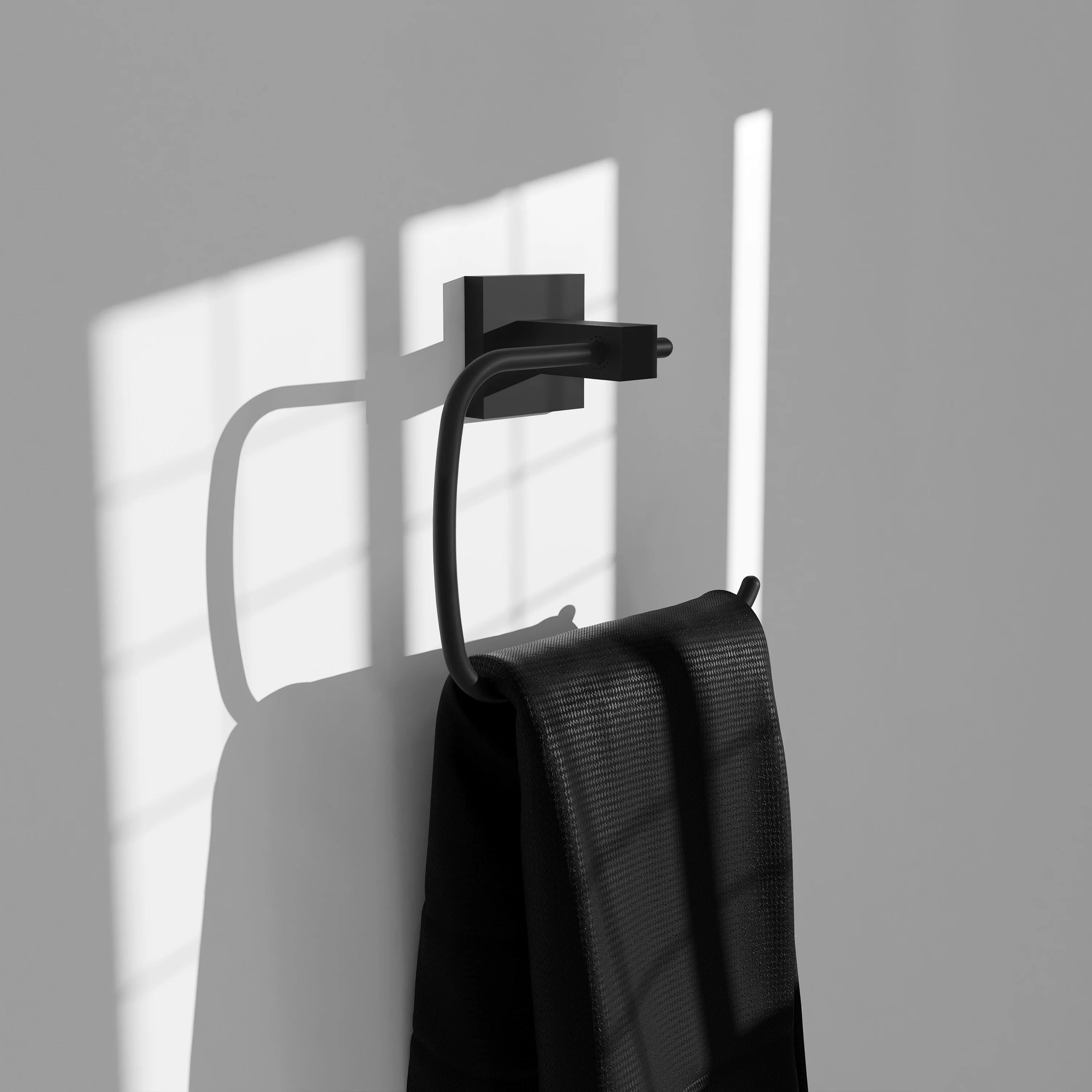 Matte black towel ring holding a folded towel on wall mount