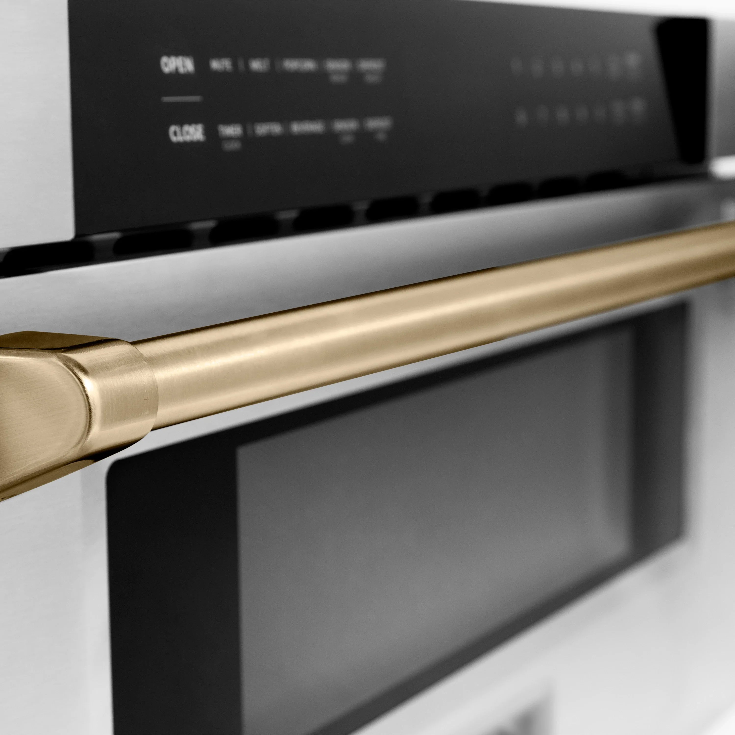Close-up gold handle on stainless microwave drawer with black control panel
