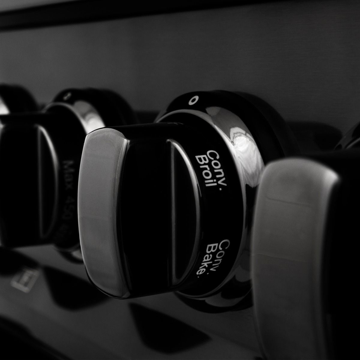 Black dual fuel range control knobs with star and swirl icons