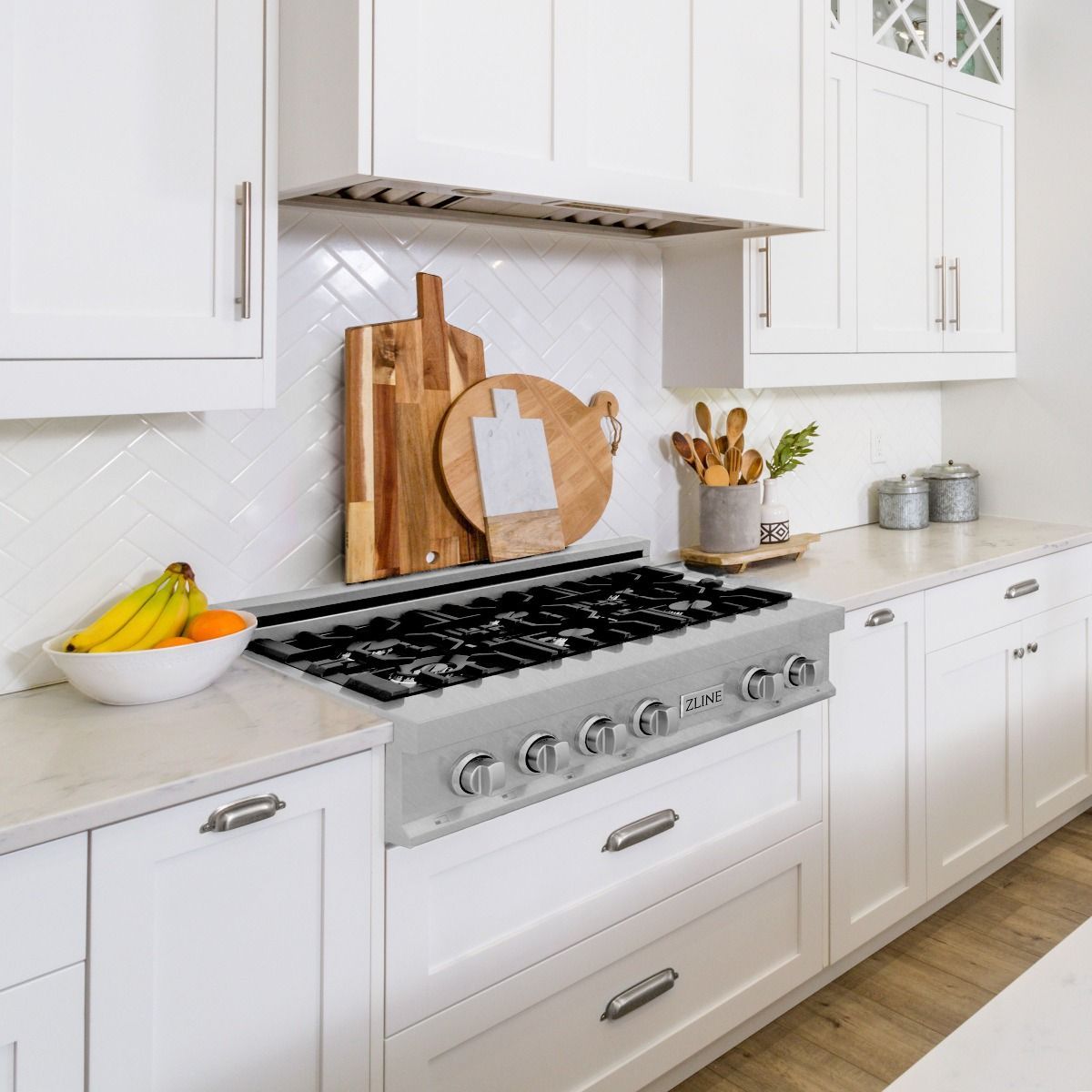 Stainless steel gas range with black burner grates and control knobs in a kitchen