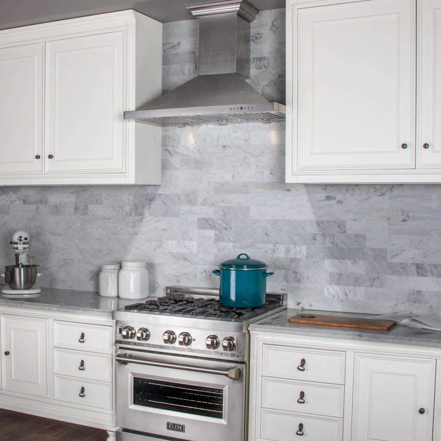 Satin stainless steel range hood over gas cooktop with burner grates and control panel