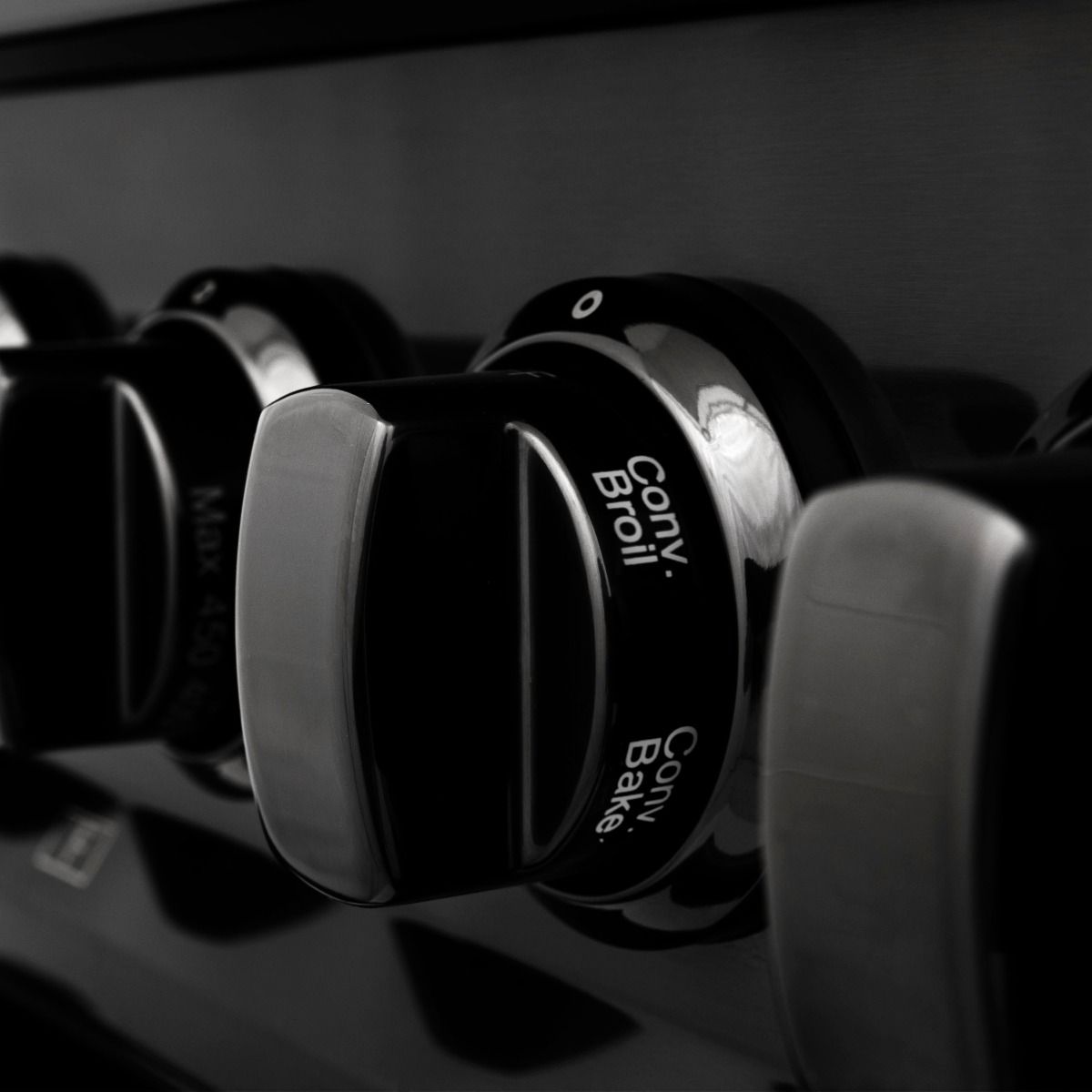 Dual fuel range control knobs with engraved settings, close-up in black finish