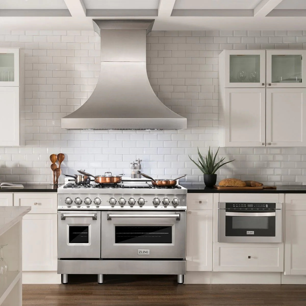 Stainless steel dual fuel range with black grates and overhead vent hood