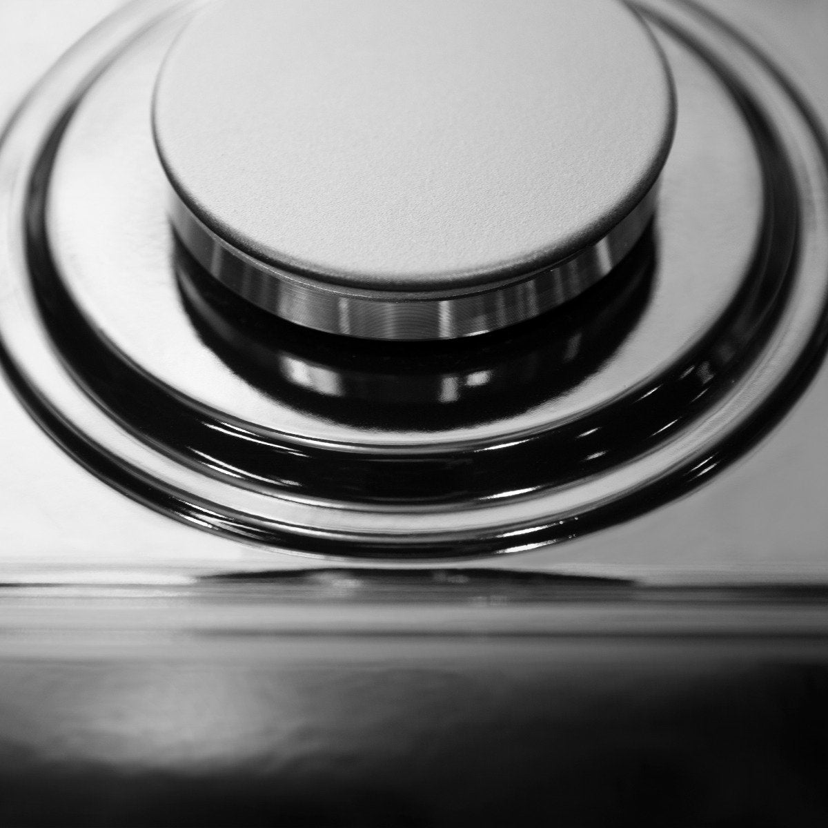 Stainless steel burner cap with black burner ring, close-up