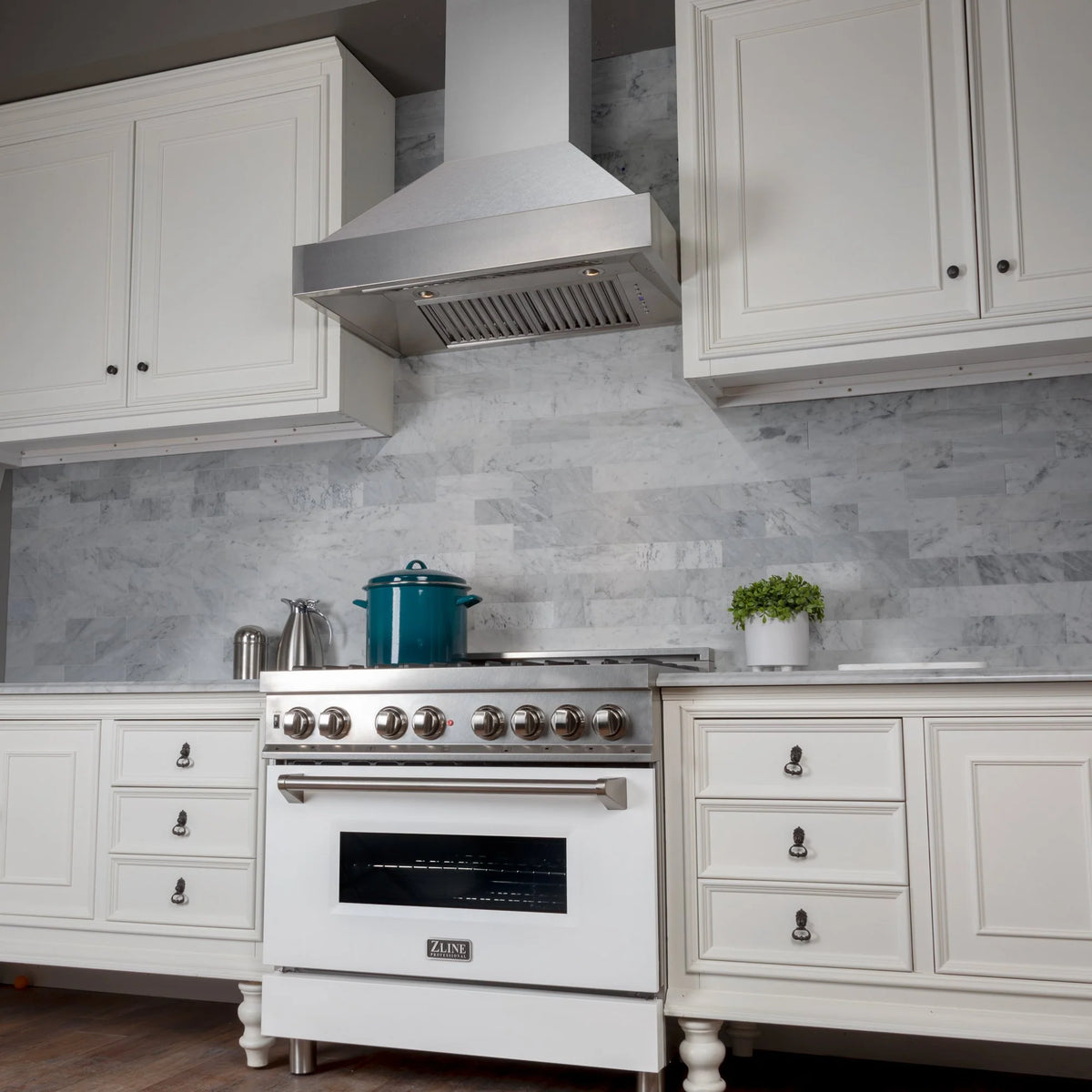 Stainless steel wall hood paired with white gas range and burner control knobs