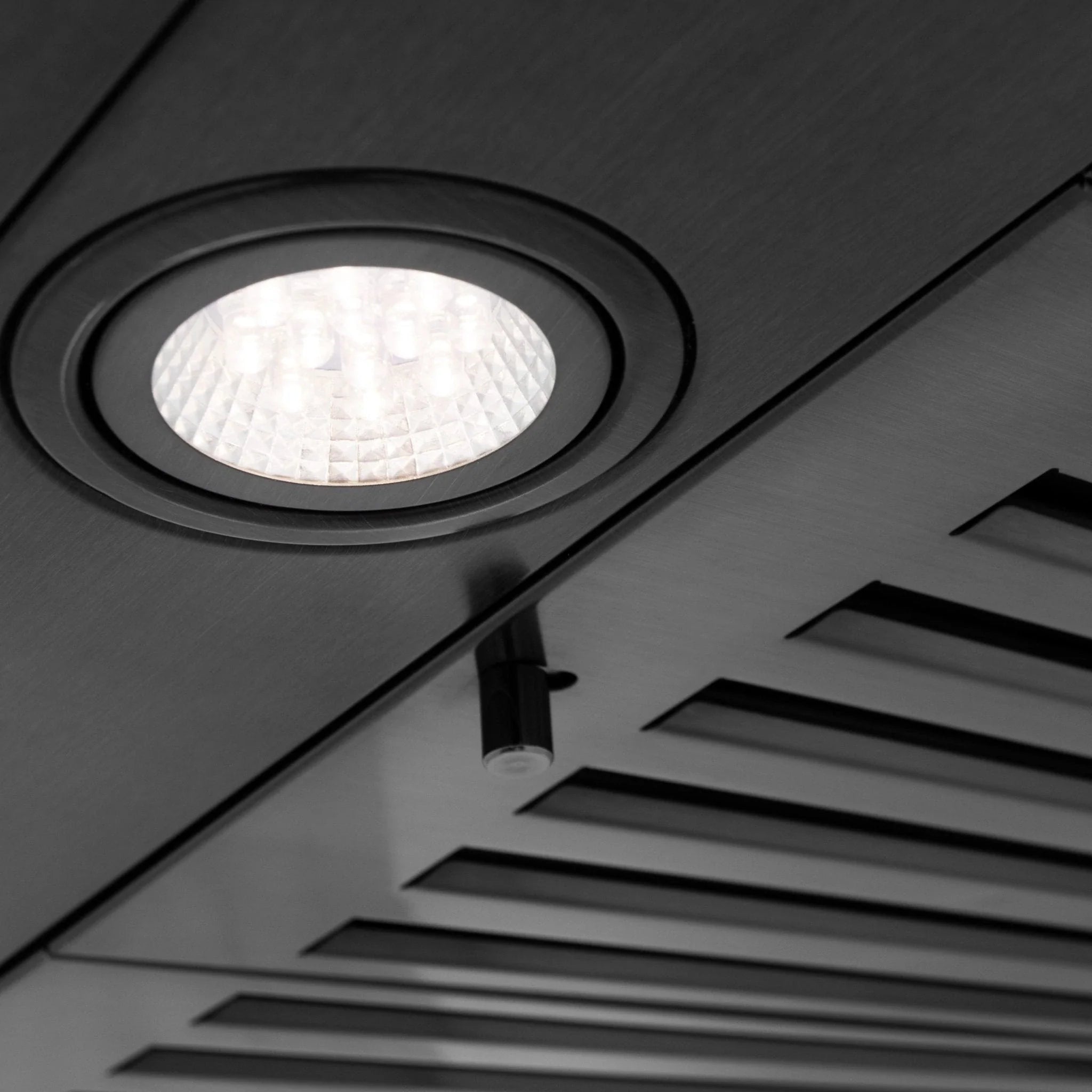 Black stainless steel range hood recessed LED light in circular trim bezel.