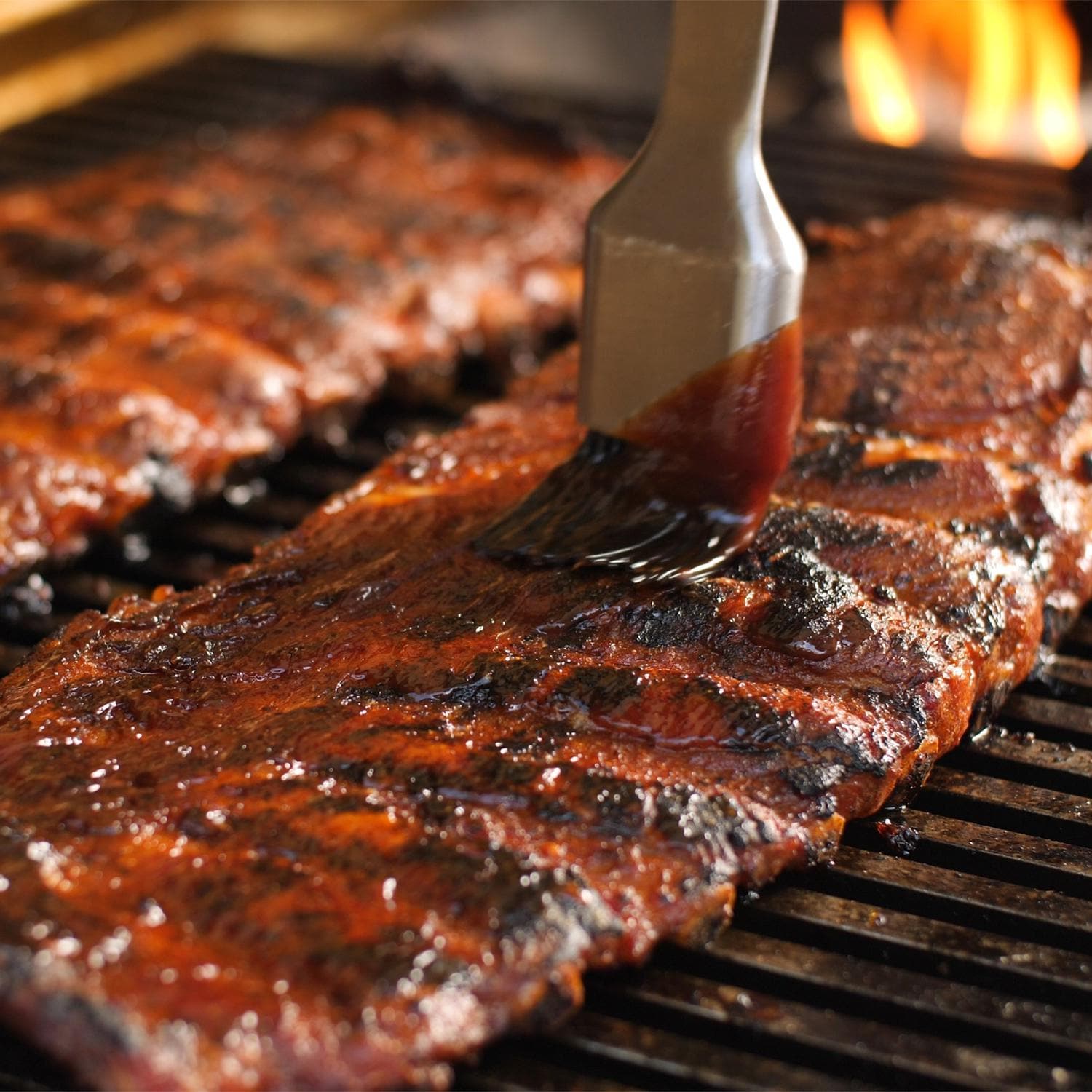 Natural gas built-in grill close-up with spatula and glazed meat on grates
