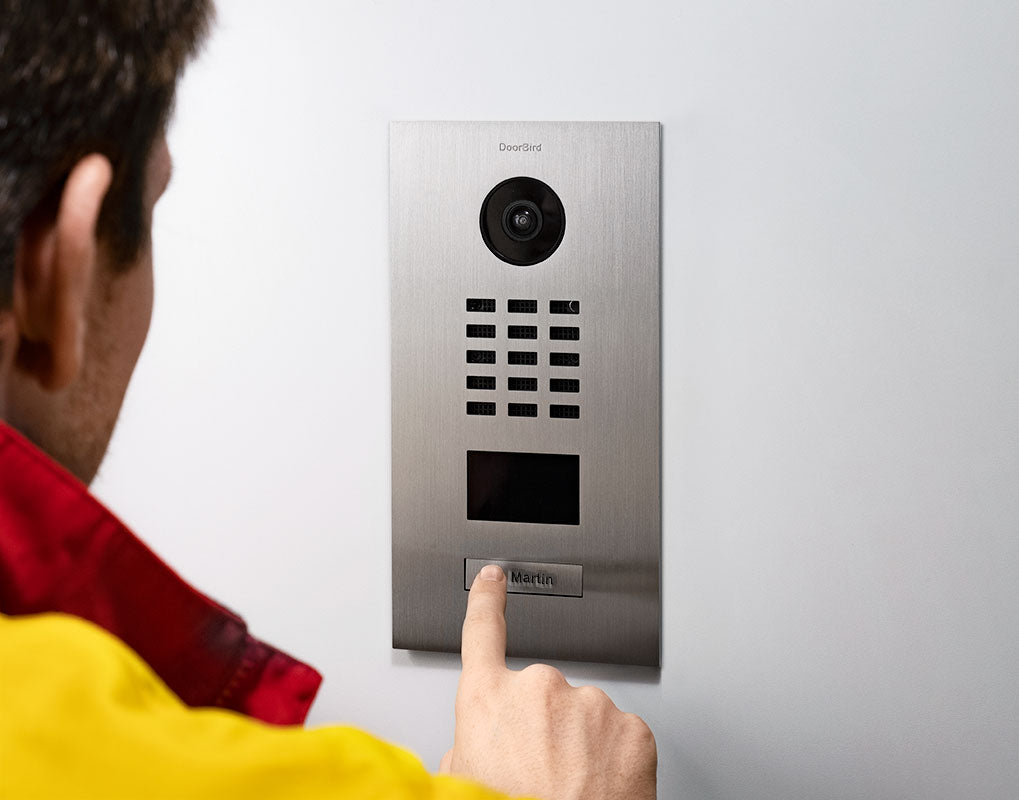 Hand pressing button on stainless steel video door station with camera and keypad